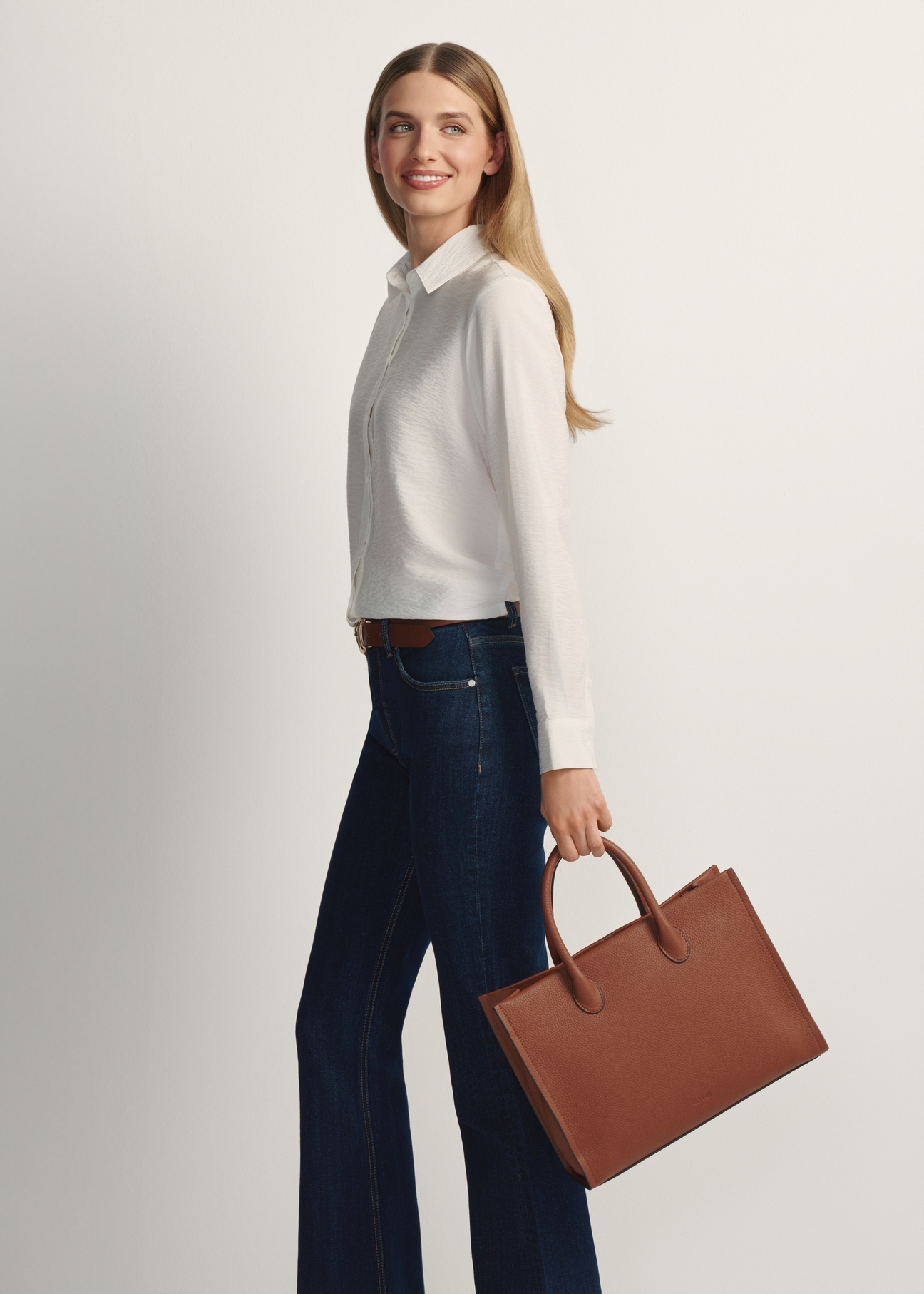 TORES-1206-1D(W26), camel-colored leather handbag. View of the product in the model's hand. Full-length silhouette visible.