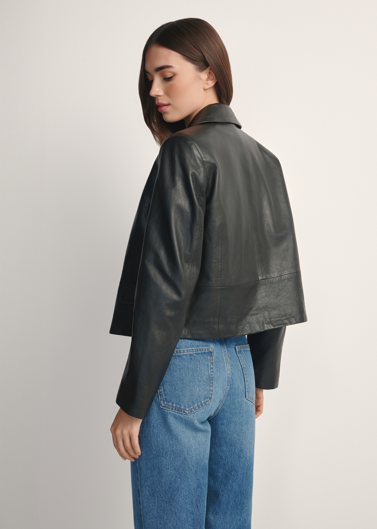 Black short women's leather jacket KURDS-0598-99(W26), product view from the back on the model, half of the silhouette visible.