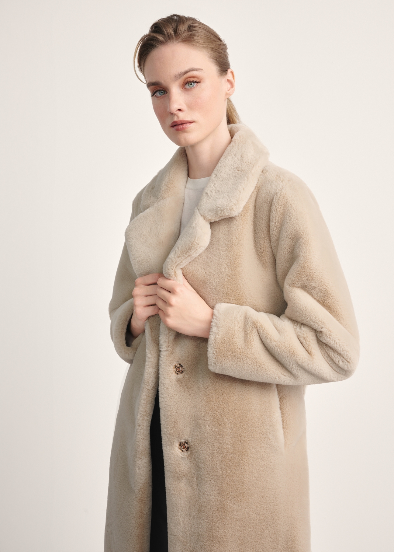 Women's faux fur coat with a belt FUTDP-0002A-81(Z24), the product is visible diagonally on the model, half of the silhouette is visible.