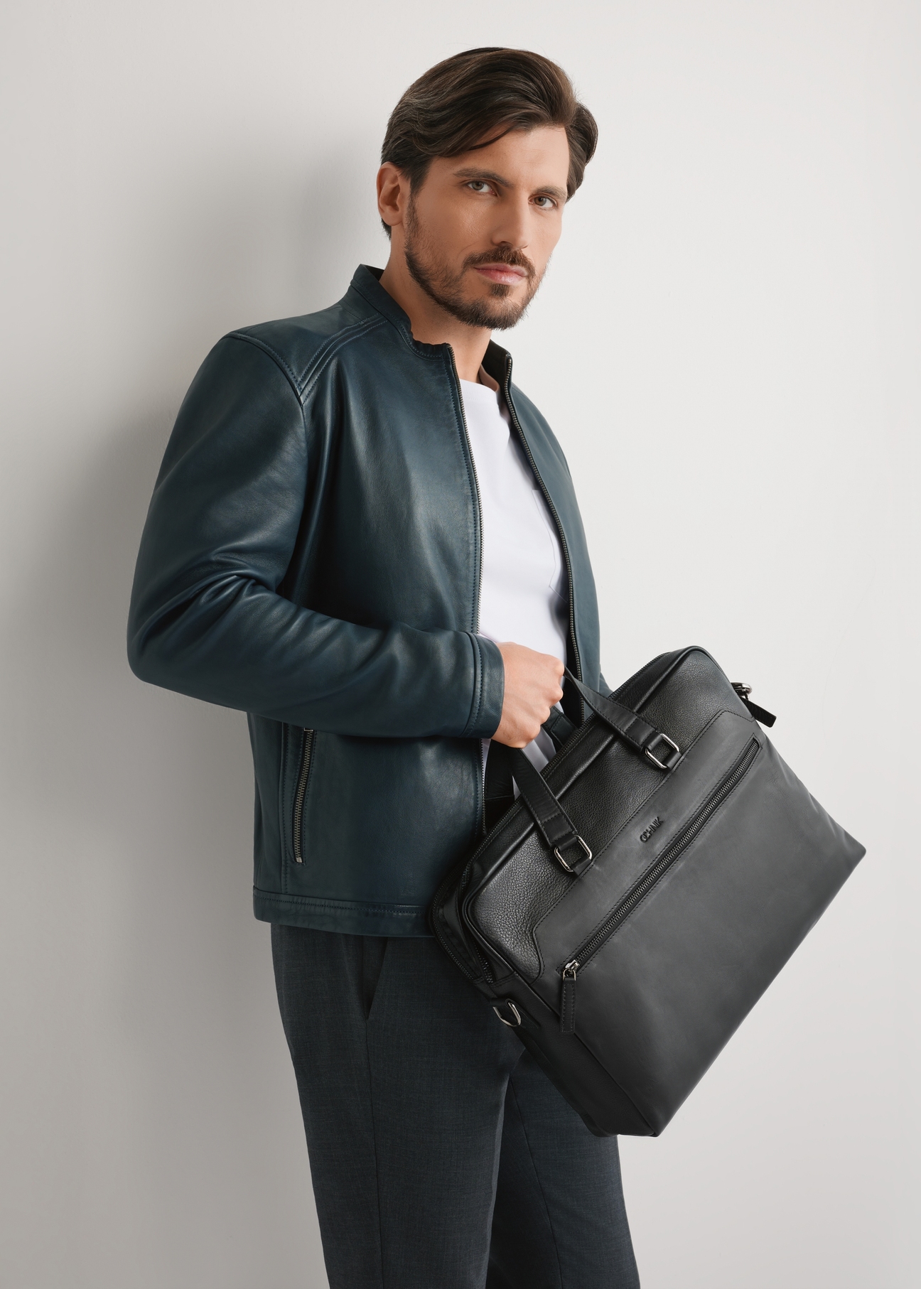 Black leather men's briefcase TORMS-0495-99(W26) - front view of the product, held by the model, against a light background. Half-length silhouette visible.