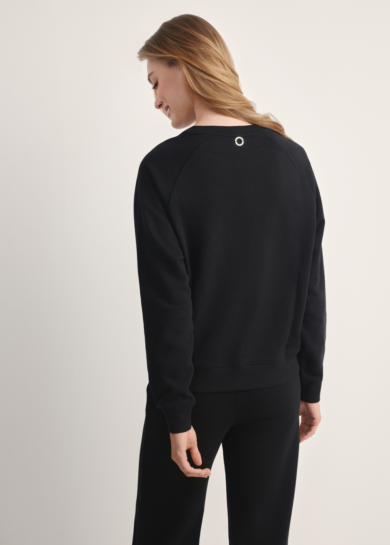 Black women's sweatshirt BLZDT-0114-99(Z25), product visible from the back on the model, half of the silhouette visible.