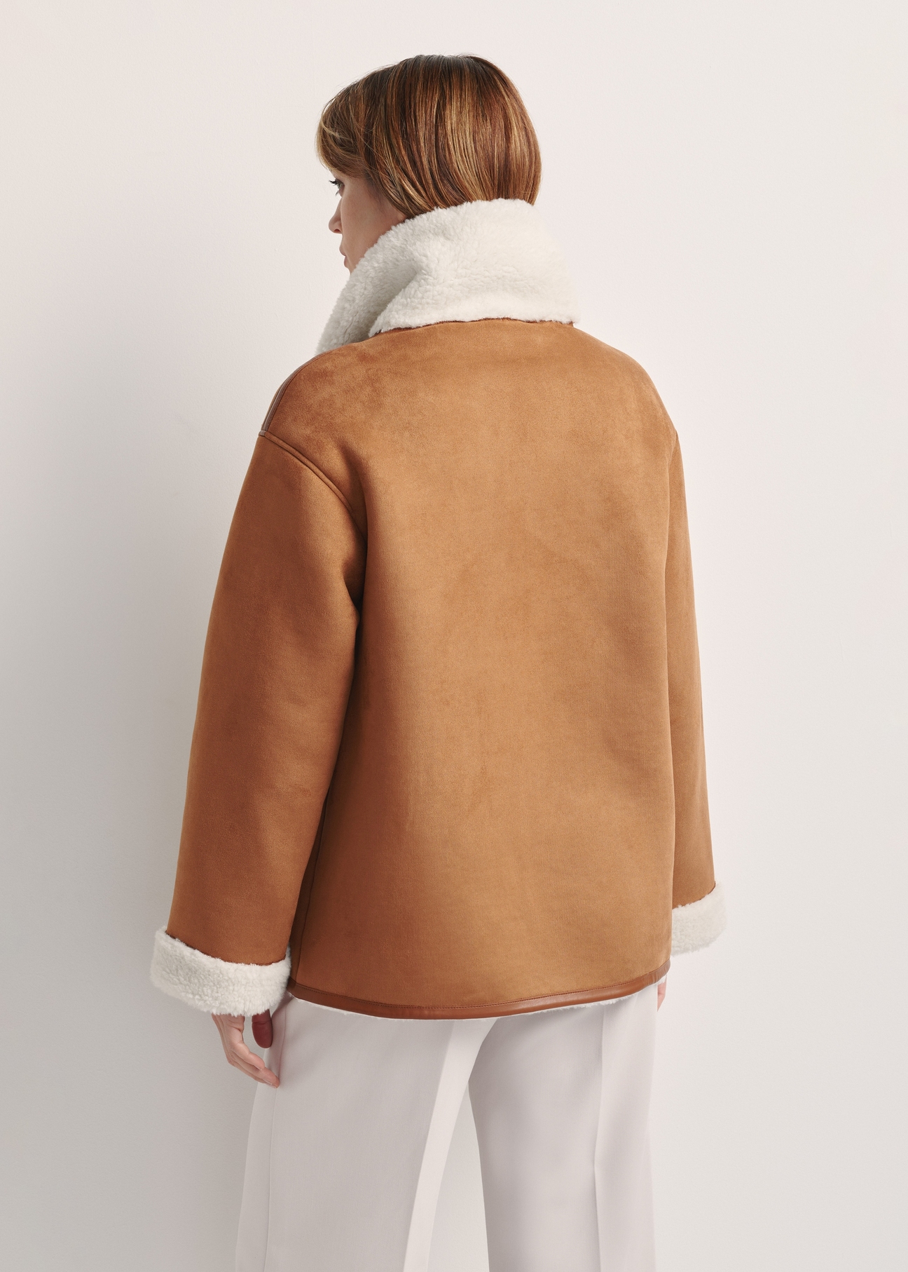 Women's sheepskin coat in camel color KOZDP-0013-24(Z25) - product view from the back on a model on a white background. Half of the silhouette visible.