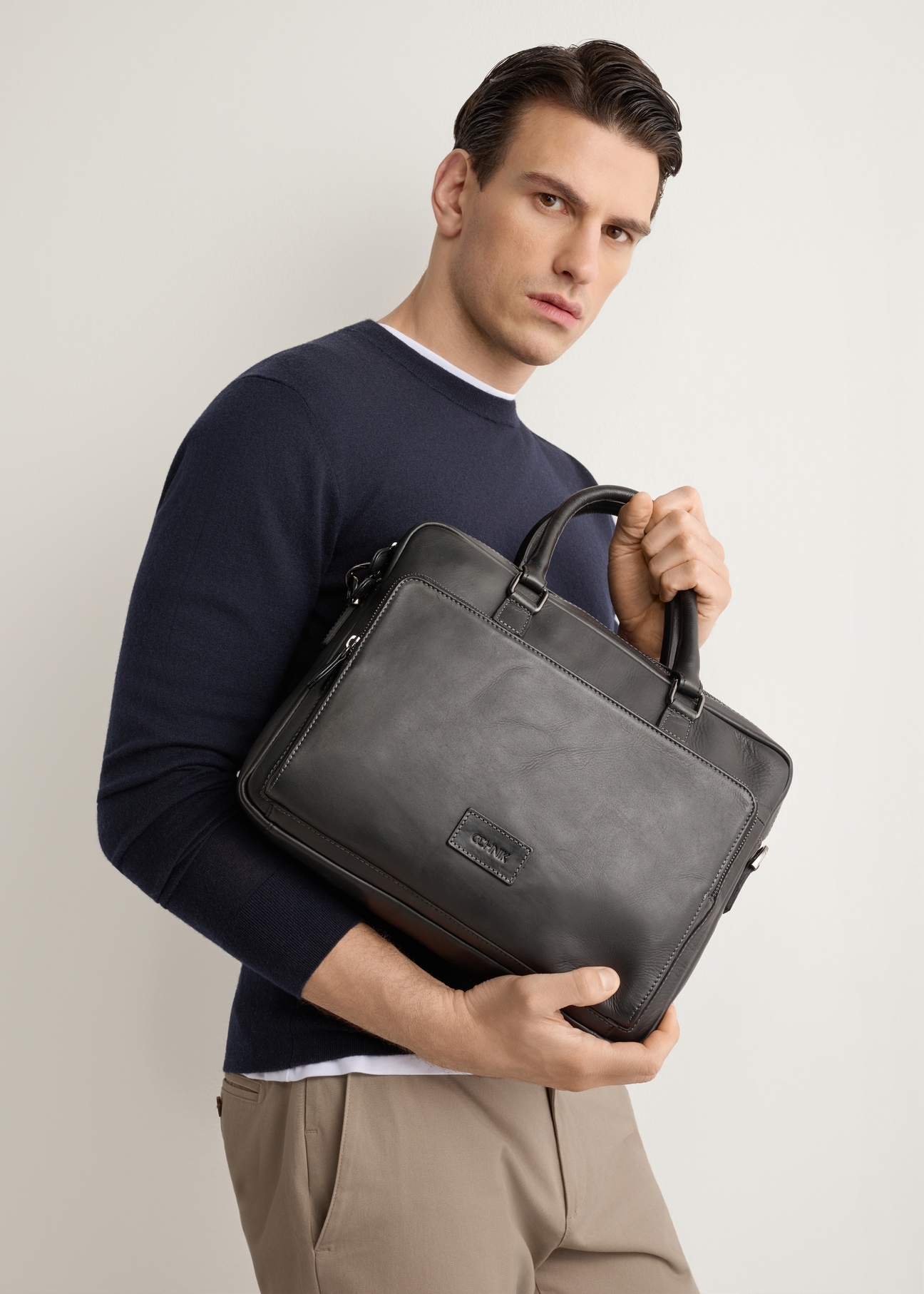 Black leather two-compartment men's bag TORMS-0525-99(Z26), product view in model's hands. Half of silhouette visible.