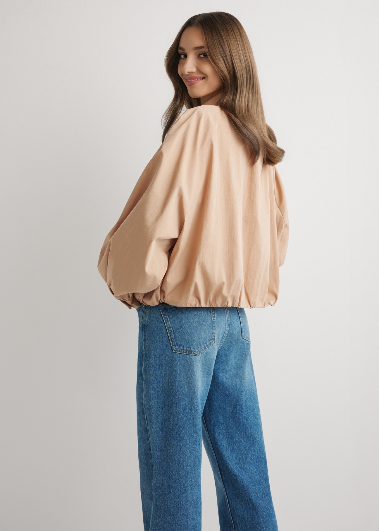 Beige short oversize women's jacket KURDT-0626-1D(W26) - back view of the product, on a model, against a light background. Knee-length silhouette visible.