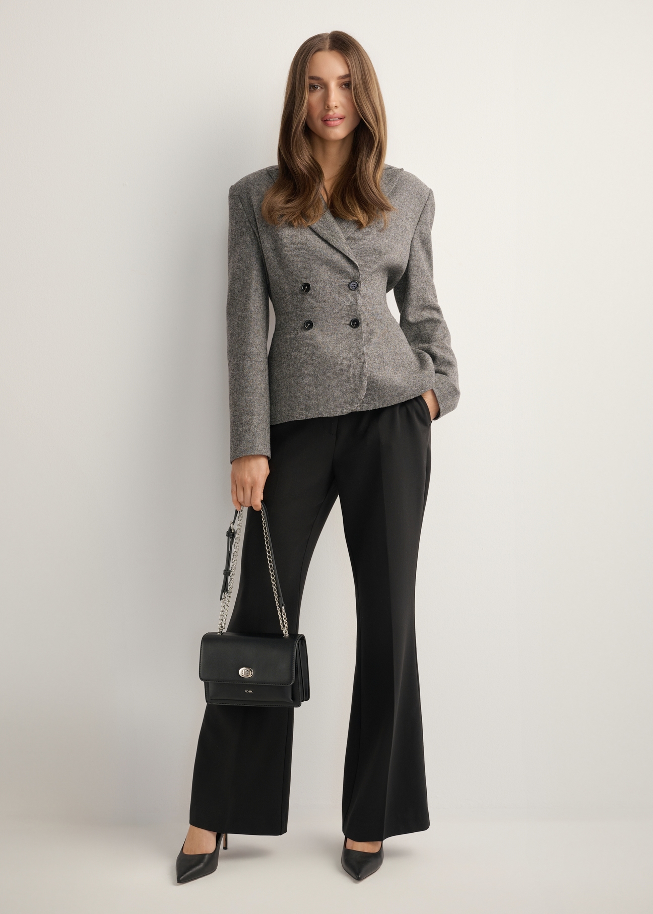 Small black women's handbag with an elegant clasp TOREC-1322-99(Z26), front view of the product on a model. Full body visible.