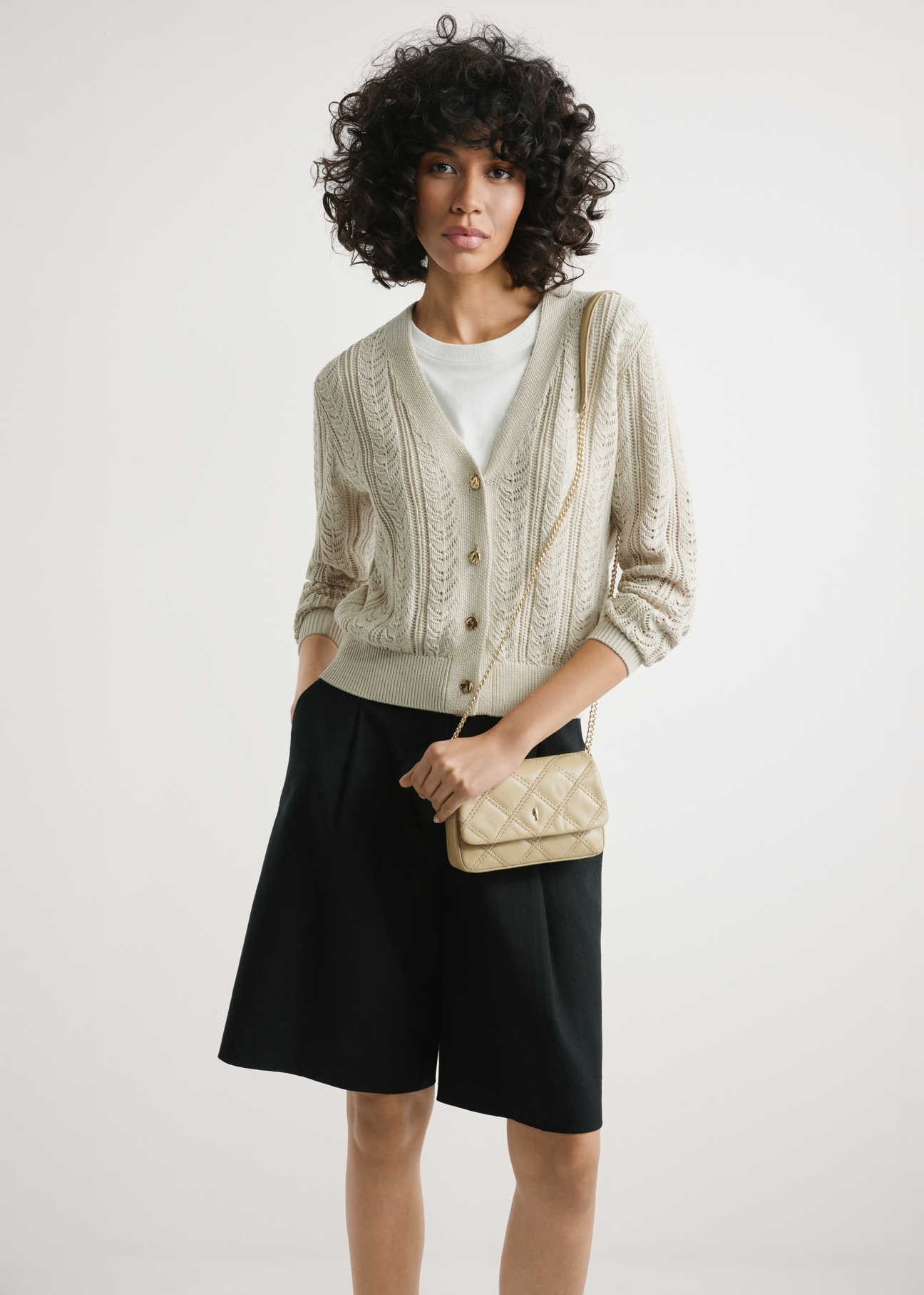 Small beige leather women's handbag TORES-1044-1B(W26) - front view of the product, on a model, against a light background. Half-length silhouette visible.