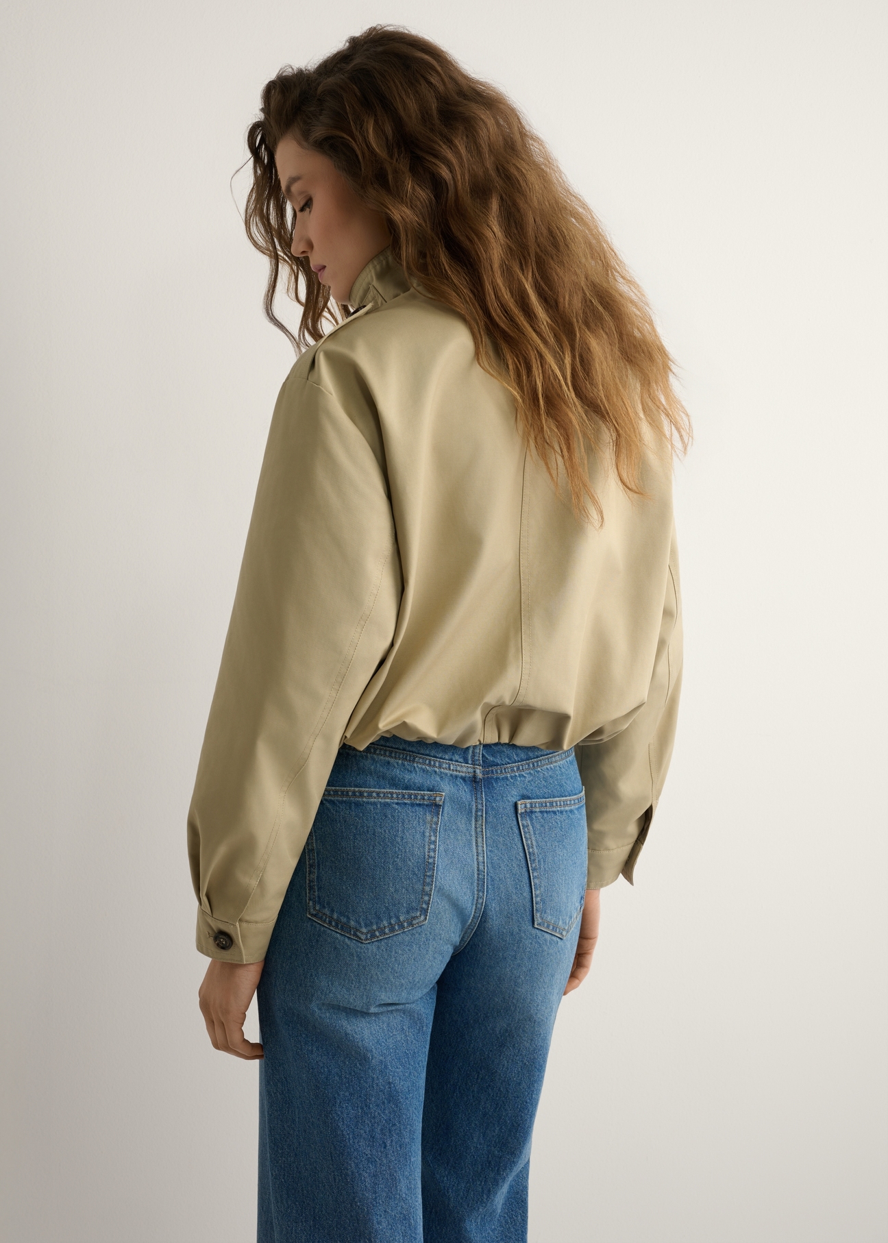 Beige women's short jacket KURDT-0657-1B(W26) - back view of the product on a model, against a light background. Knee-length silhouette visible.