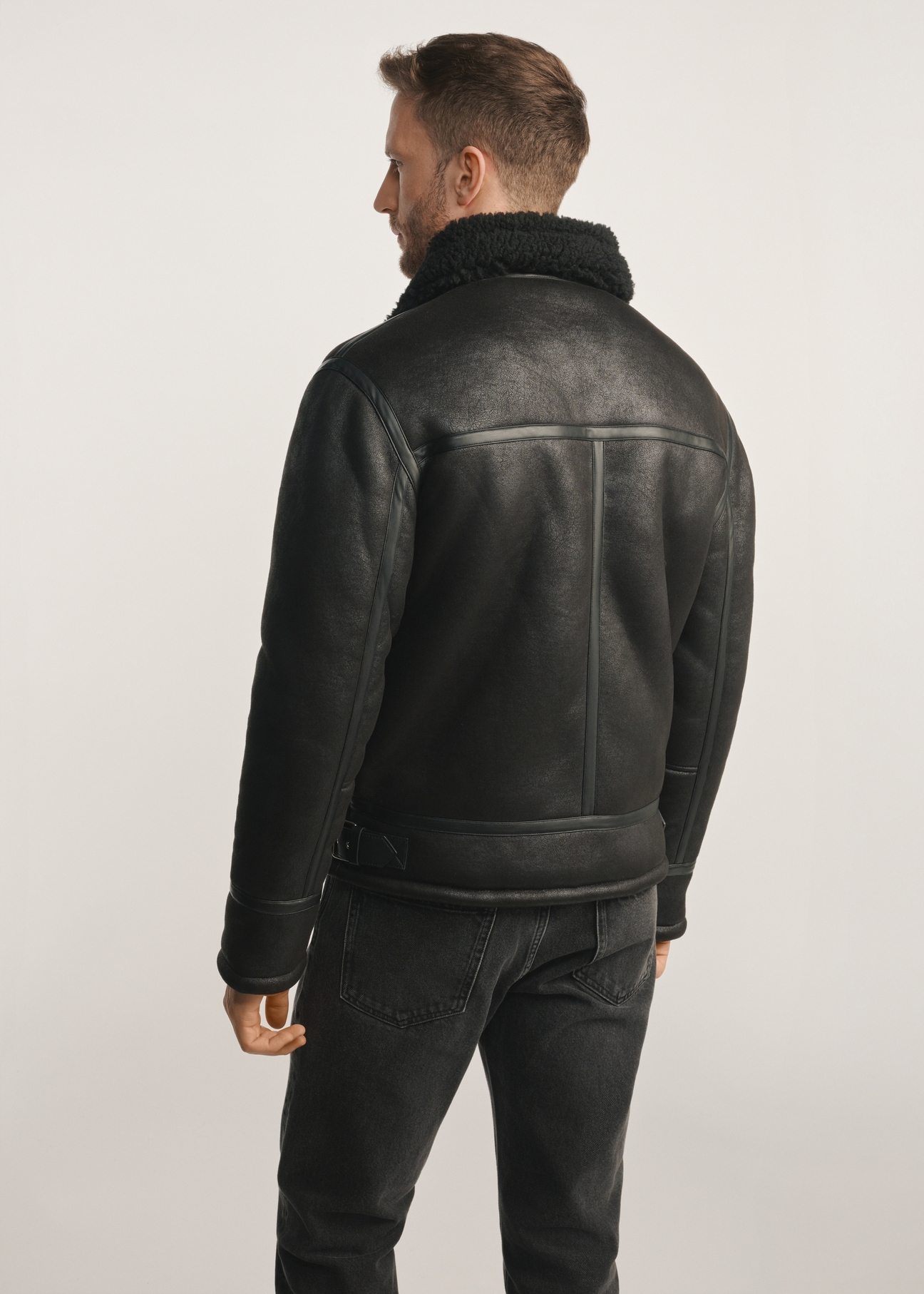 Classic black men's sheepskin coat KOZMP-0001A-99(Z24), product visible from the back on the model, half of the silhouette visible.