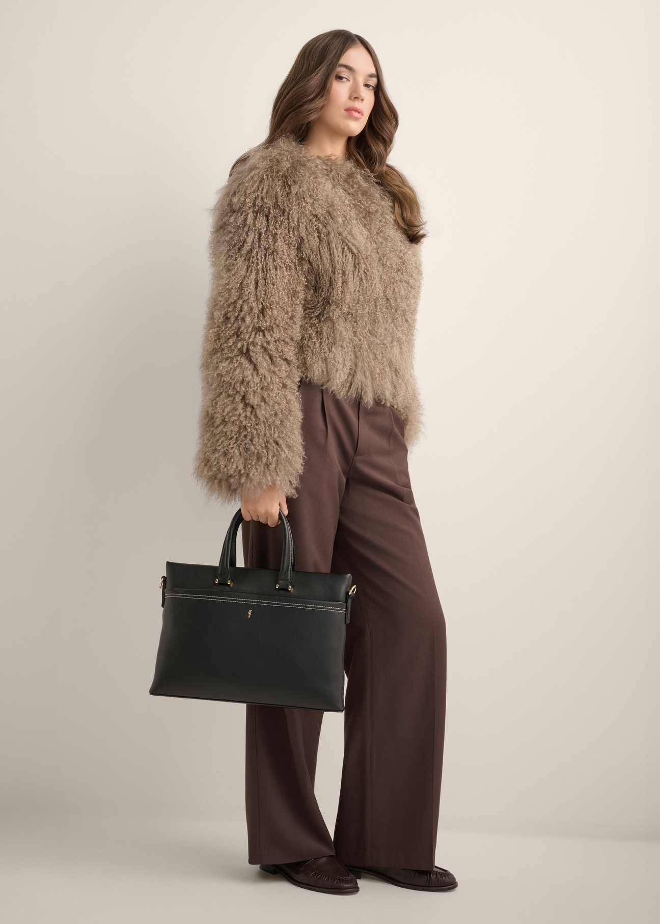 Black women's briefcase TOREC-1372-99(Z26) - view of the product, held by the model, against a light background. The entire silhouette is visible.