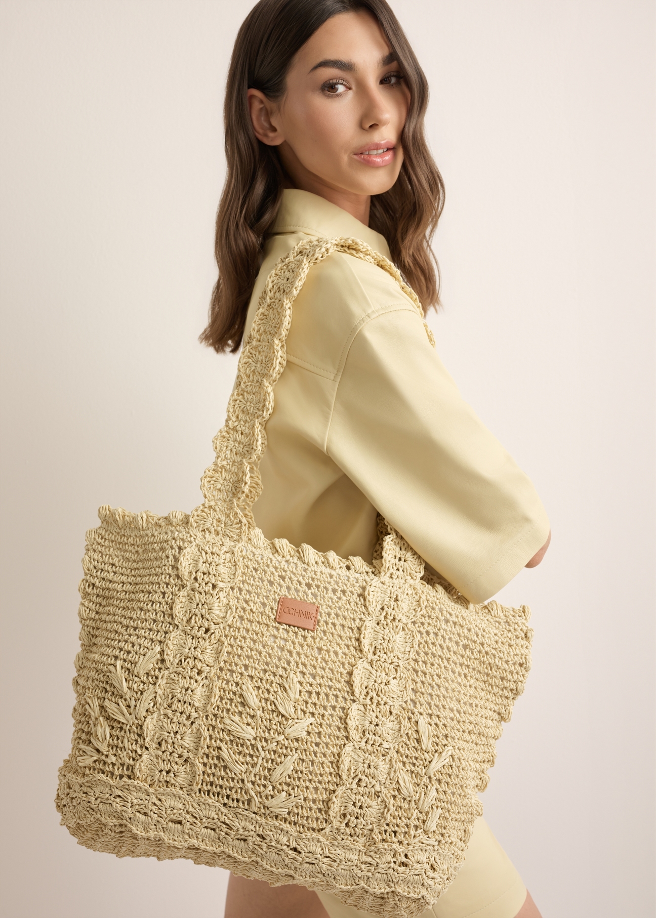 Light beige straw shopper bag TOREC-1222-1E(W26), product view on model's shoulder. Half of silhouette visible.