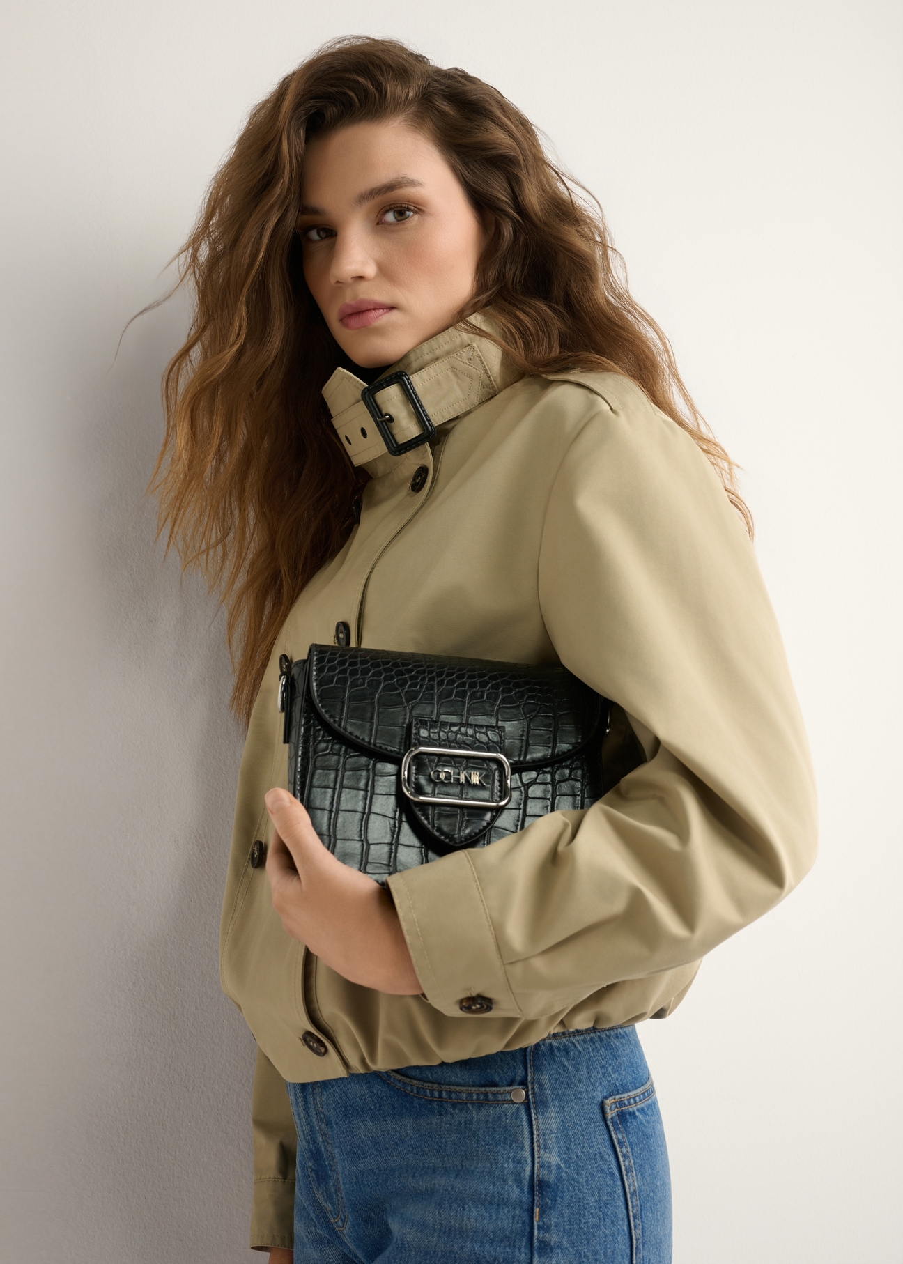 Women's black croco messenger bag TOREC-0880-9G(W26) - front view of the product, held by the model, against a light background. Half of the silhouette is visible.