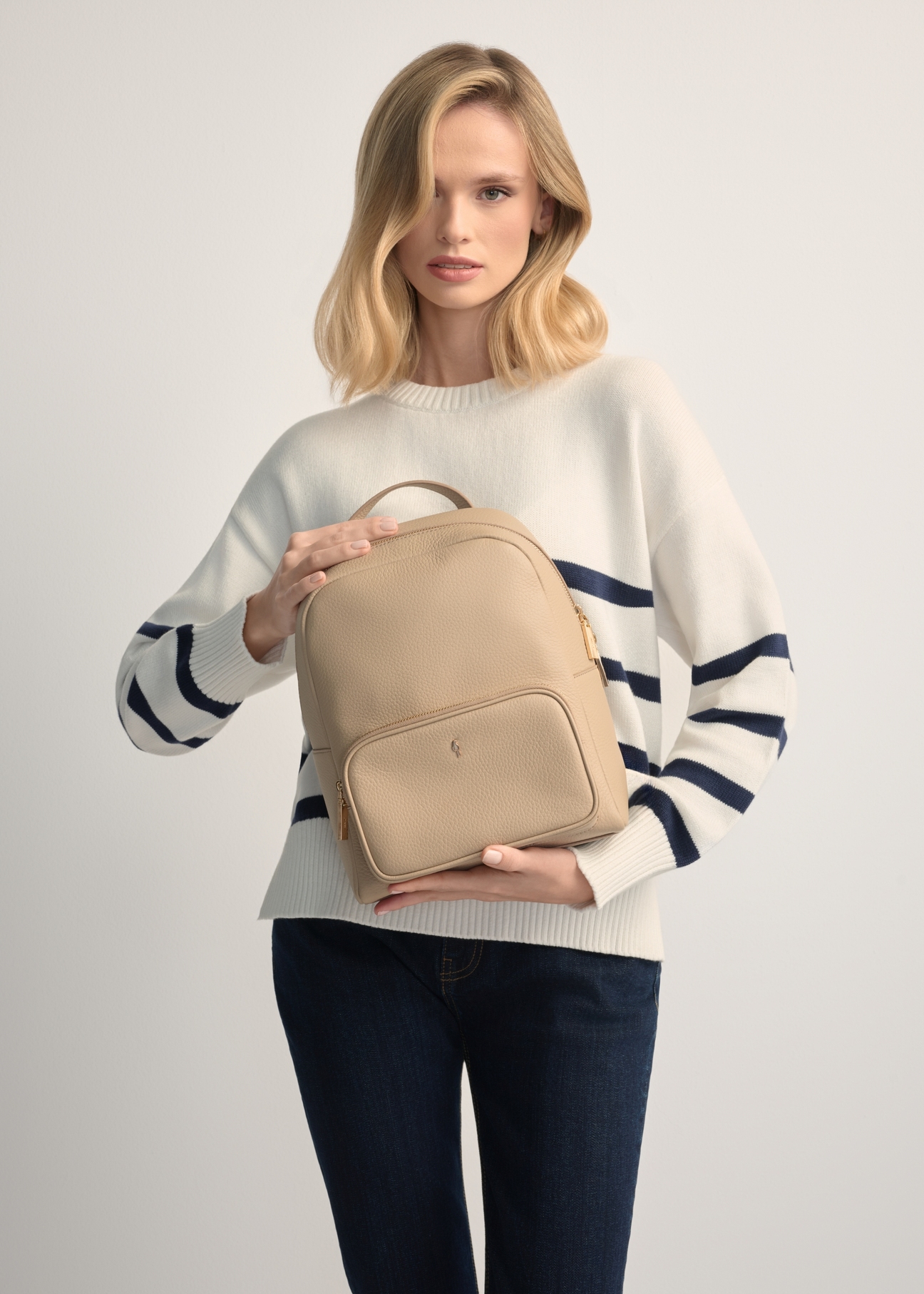 Beige leather women's backpack TORES-1072E-1B(W26), product view in model's hands. Half silhouette visible.
