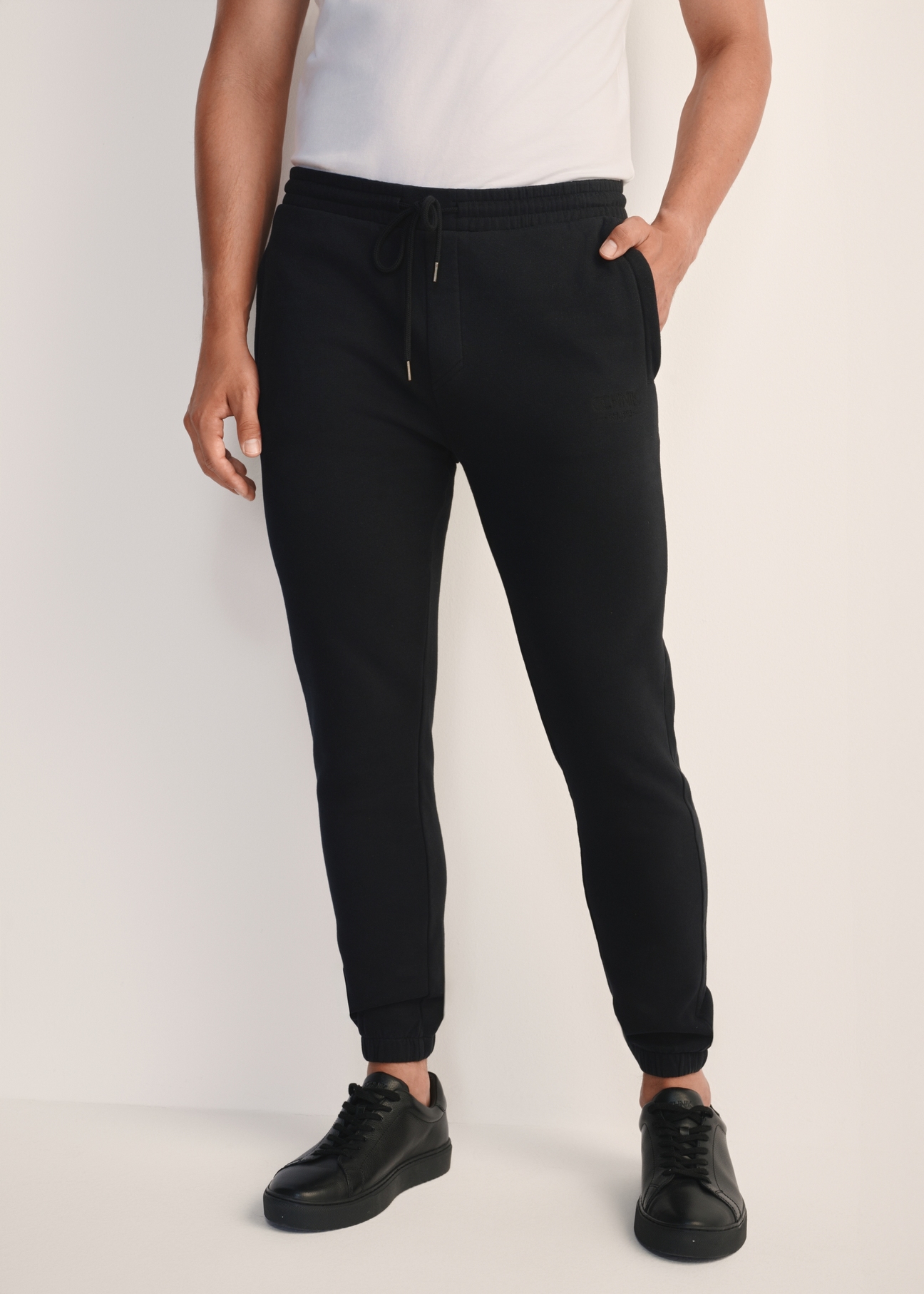 Black men's sweatpants SPOMT-0101-99(Z25), product view from the front on the model, half of the silhouette visible.