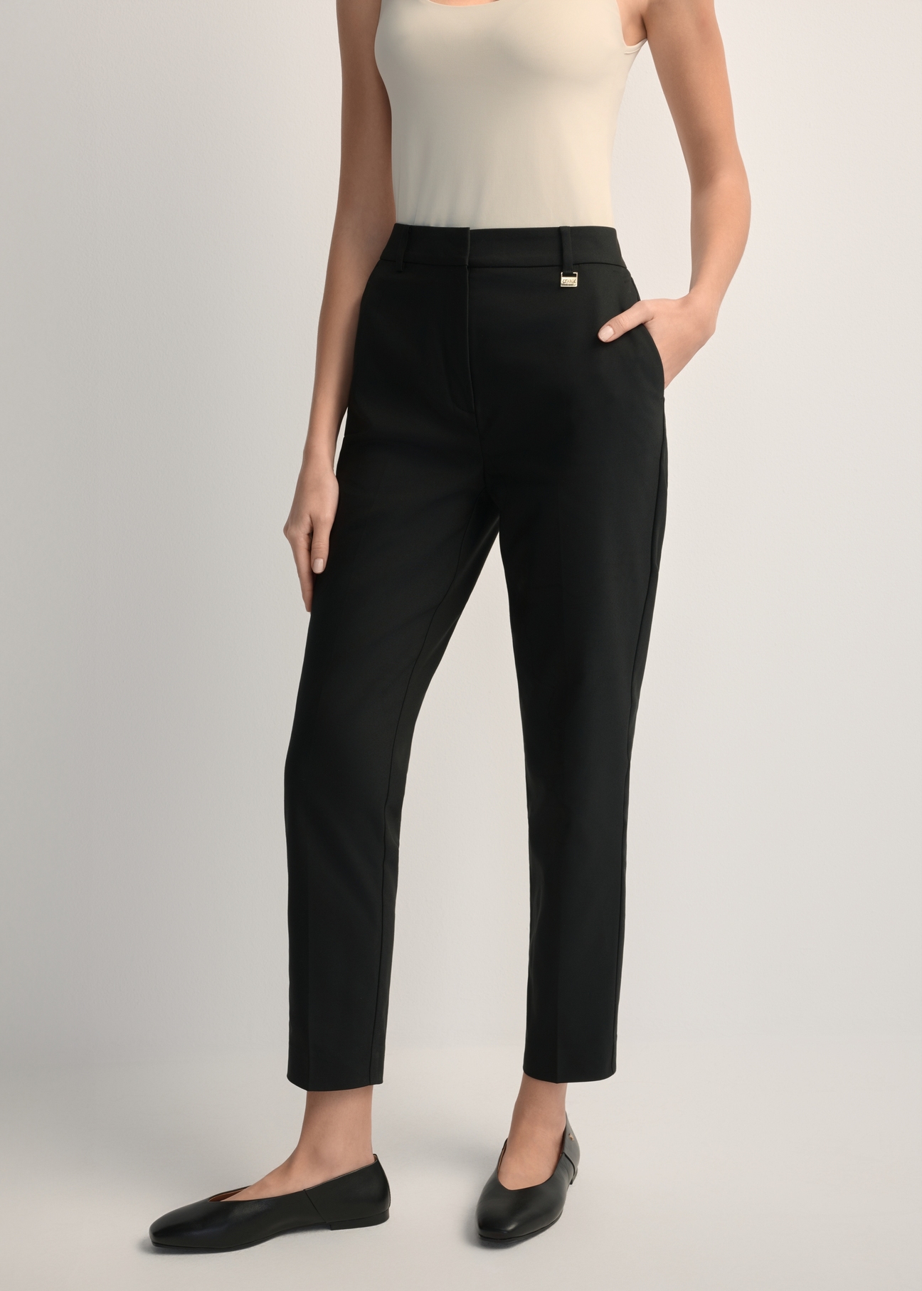 Women's black pleated trousers SPODT-0090-99(W25), front view of the product on the model. Half of the silhouette visible.