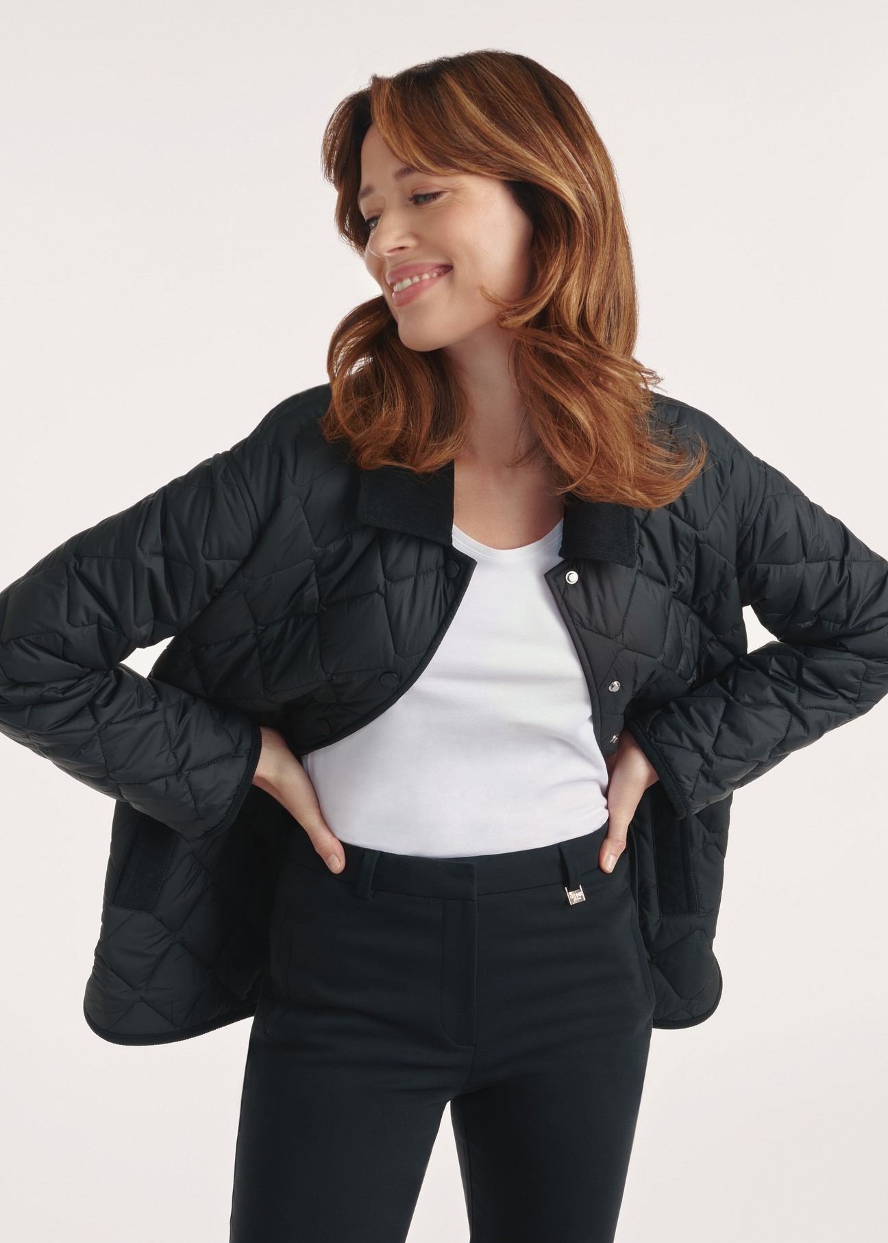 Black women's quilted jacket with hood KURDT-0588-99(Z25), front view of the product on the model, half of the silhouette visible.-02