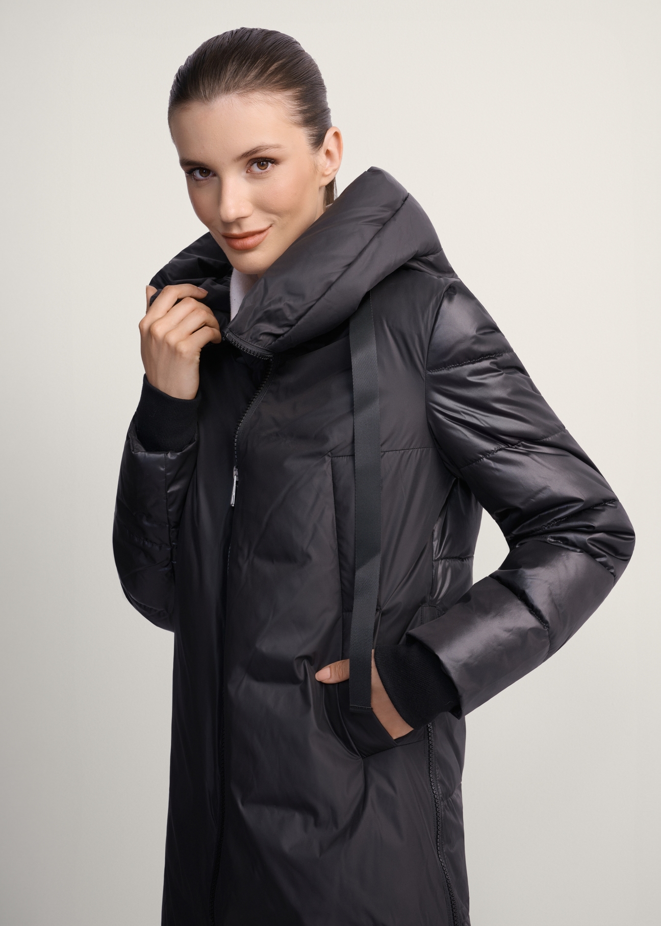 Women's black winter jacket with hood KURDT-0478-99(Z25), front view of the product on the model. Half of the silhouette visible.