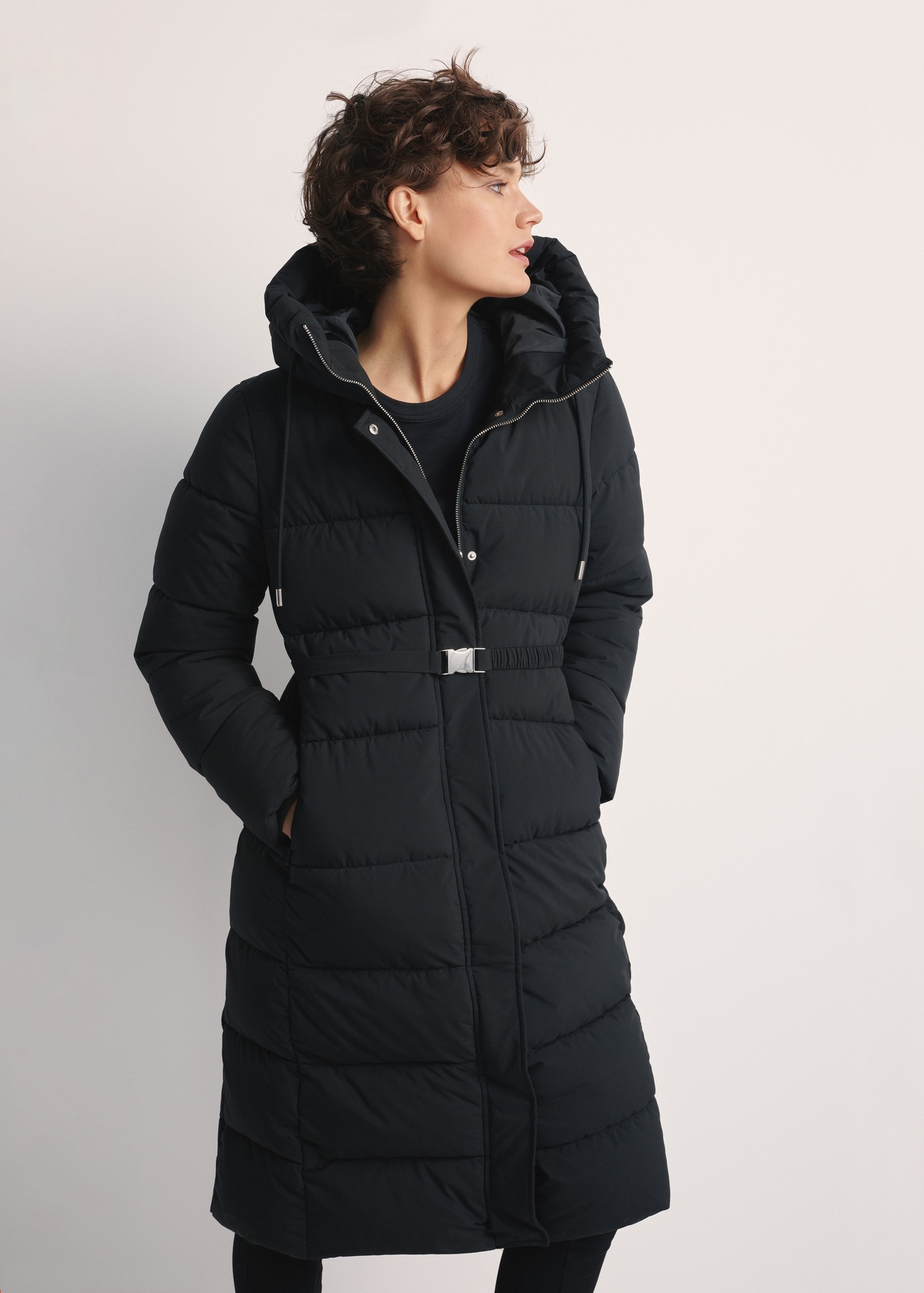 Long black women's jacket KURDT-0602-99(Z25), front view of the product on the model. Half of the silhouette visible.