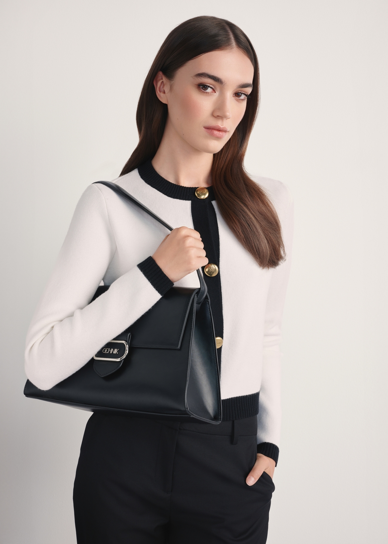 Elegant black women's handbag TOREC-1068-99(Z25) - diagonal view of the product on a model, against a white background. Half of the silhouette is visible from the side.
