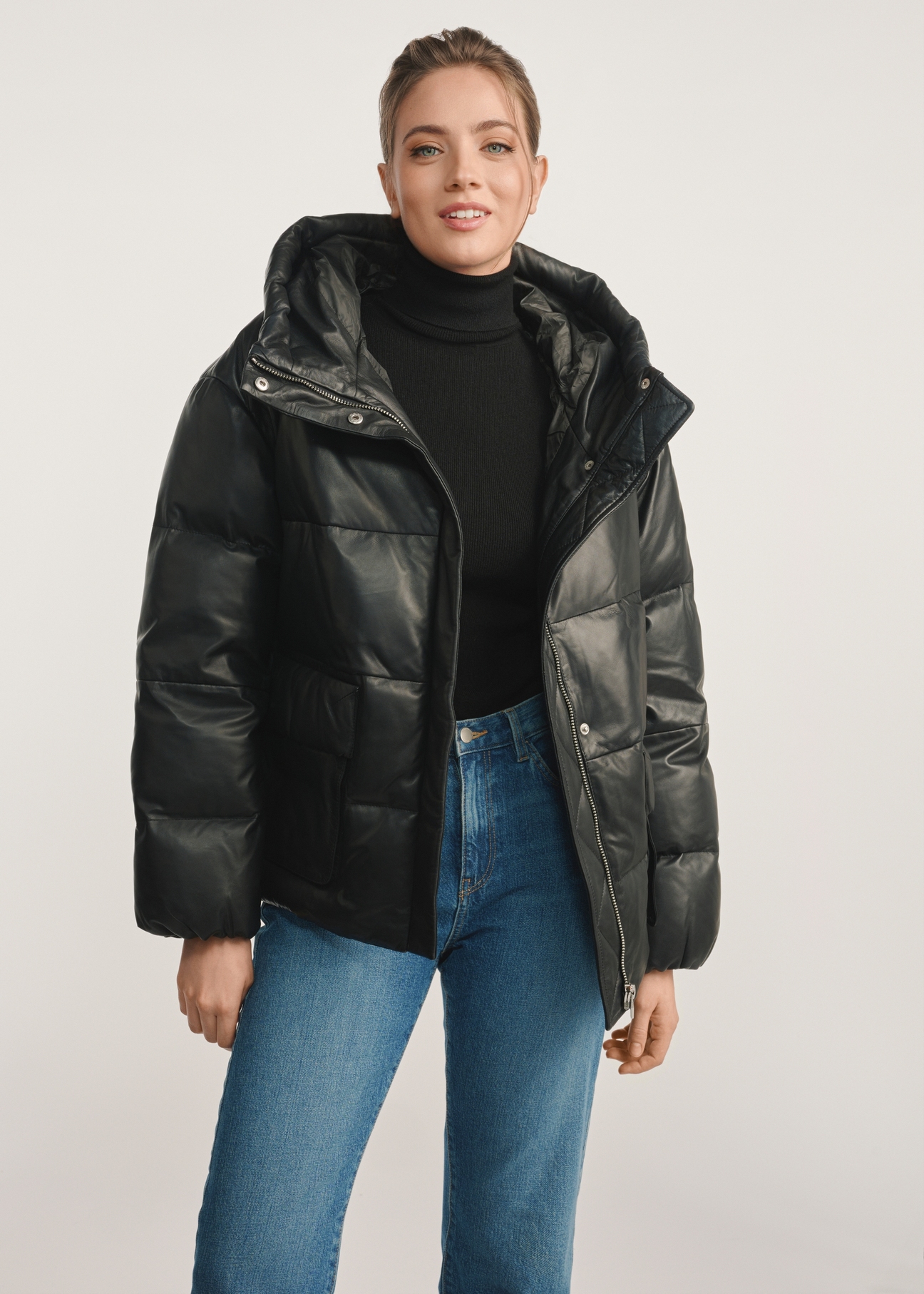 Women's black insulated leather jacket KURDS-0561-5344(Z25) - front product view of a model against a white background. Knee-length silhouette visible.
