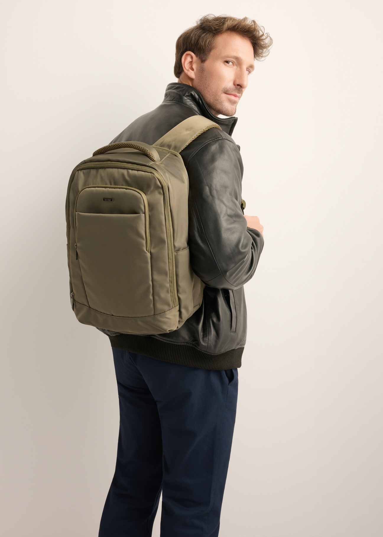 Khaki airplane backpack PLCMN-0014-8D(Z26), front view of the product on the model, half of the silhouette visible.
