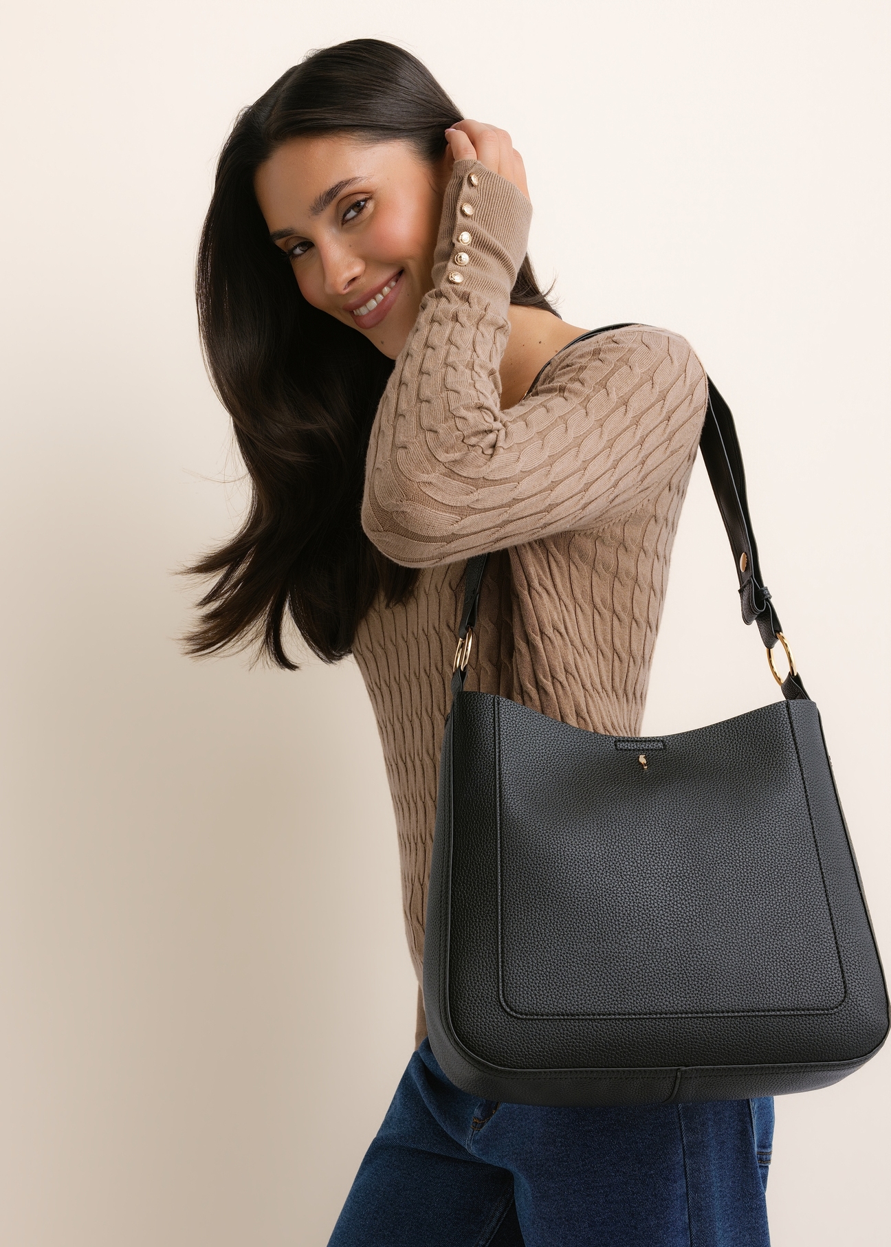 Black women's hobo bag TOREC-1257-9I(Z26), diagonal view of the product, on a model, on a light background. Half of the silhouette visible.