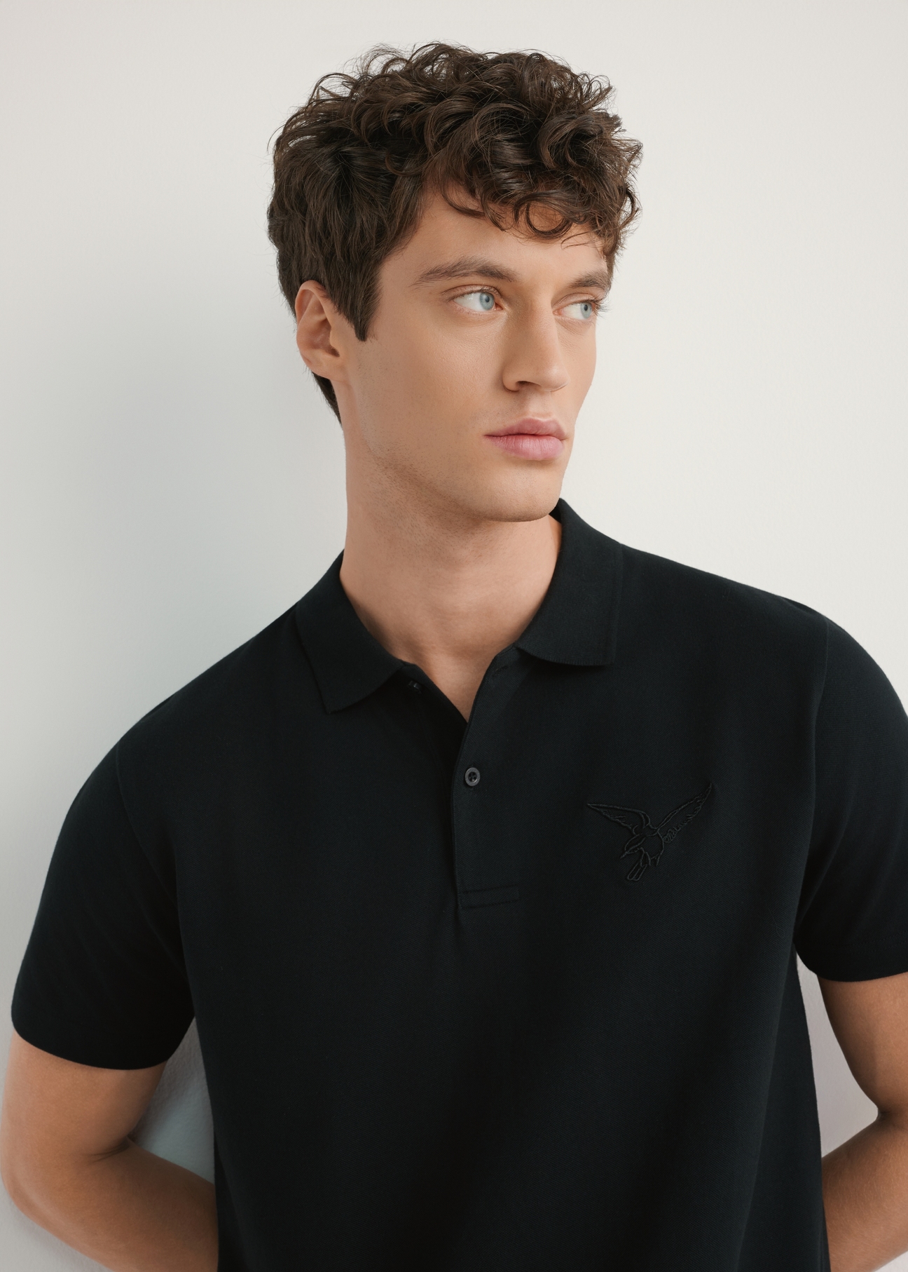 Men's black polo shirt POLMT-0084-99(W26) - front view of the product, on a model, against a light background. Half of the silhouette visible.
