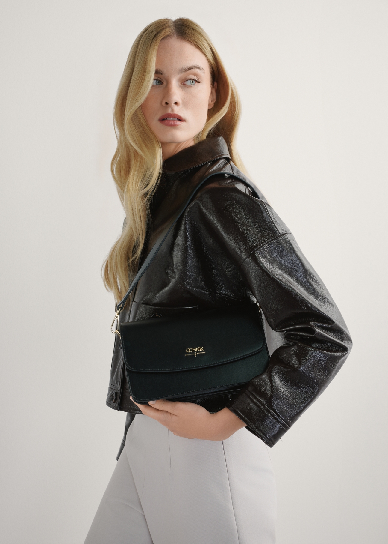 Black women's imitation leather handbag TOREC-1081-99(W26), product view in model's hands. Half of silhouette visible.