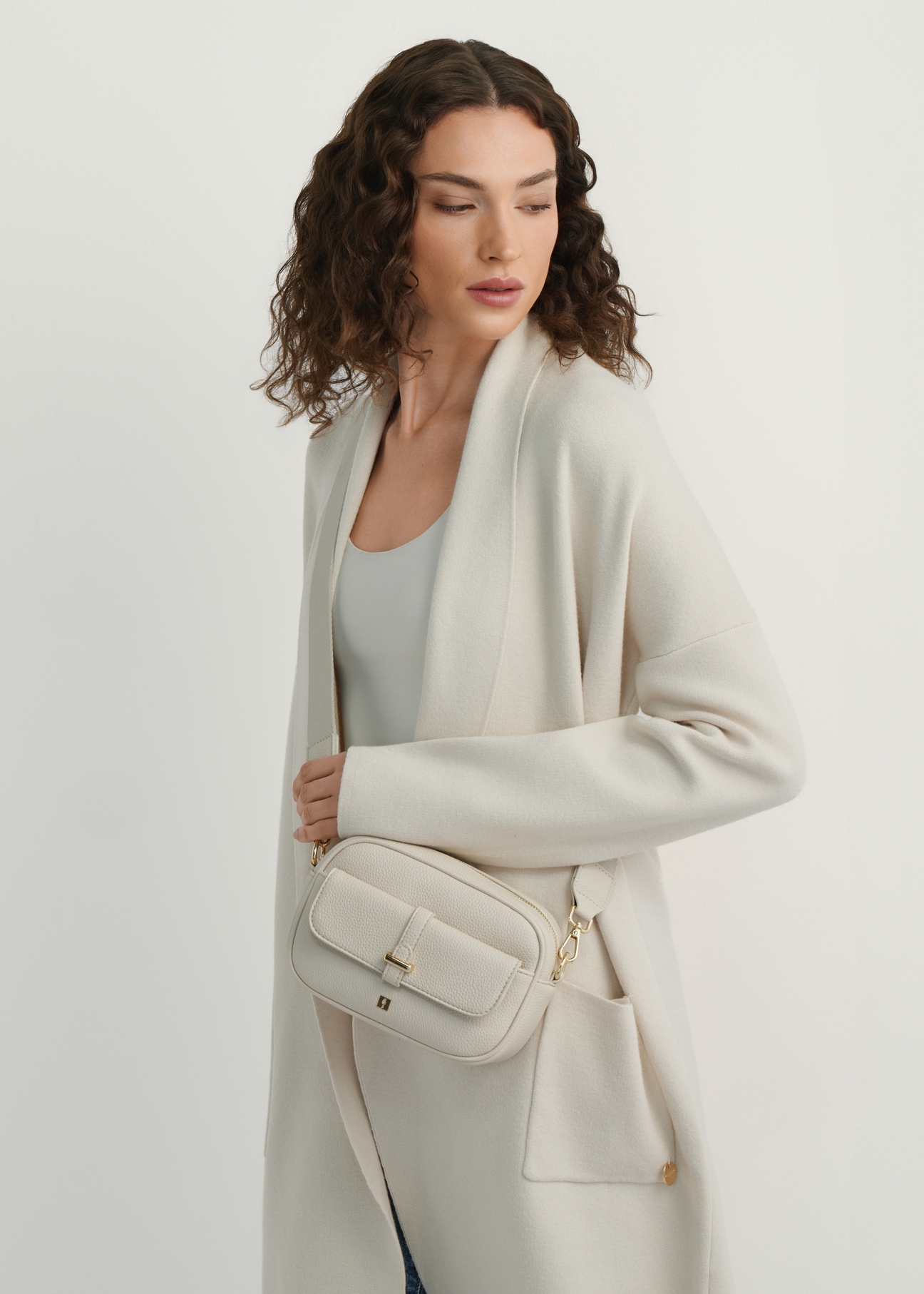 Small cream women's handbag TOREC-1174-0B(W26), product view on model's shoulder. Half of silhouette visible.