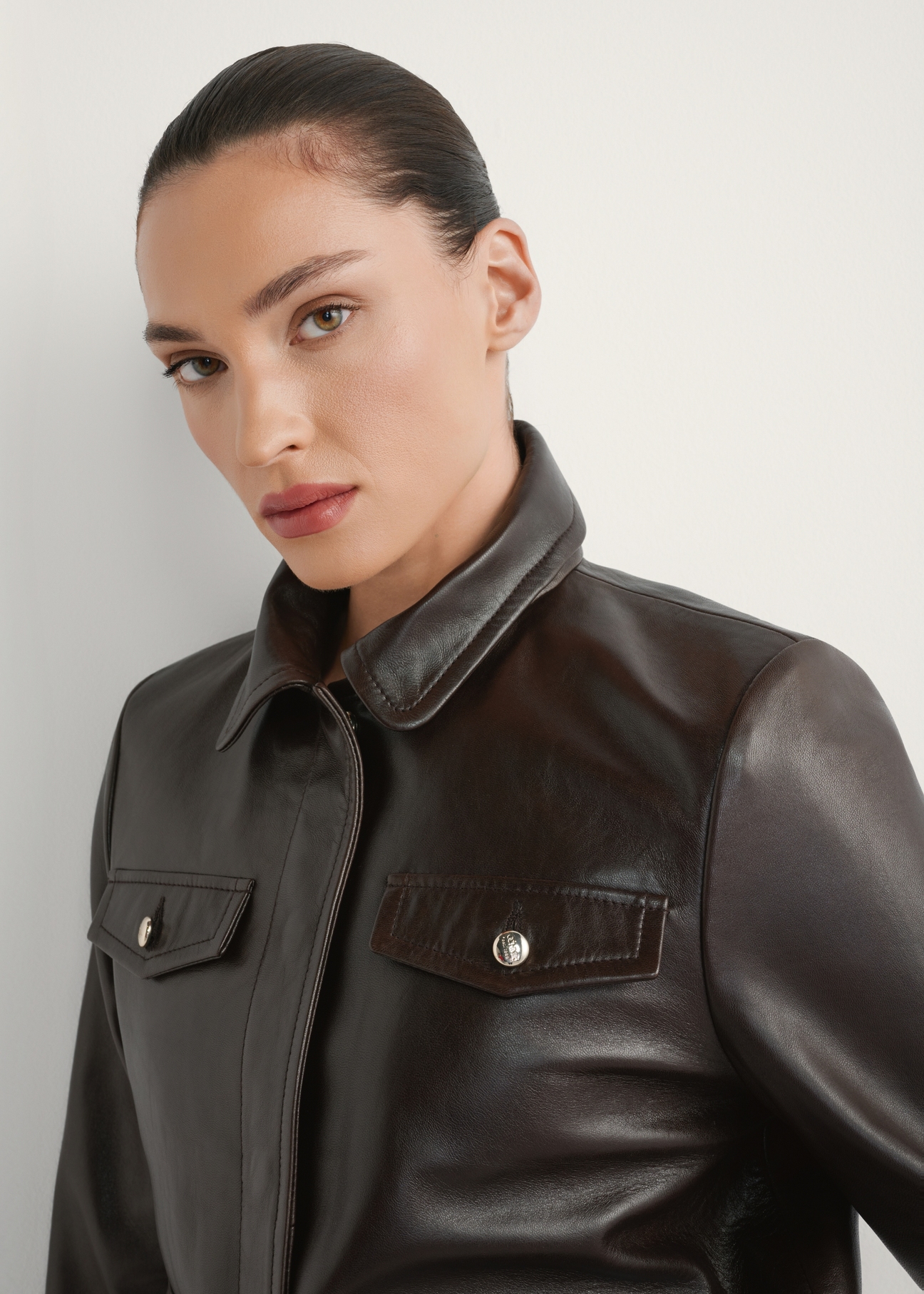 Dark brown women's leather jacket KURDS-0589-1I(W26), close-up of the product detail on the model's silhouette.