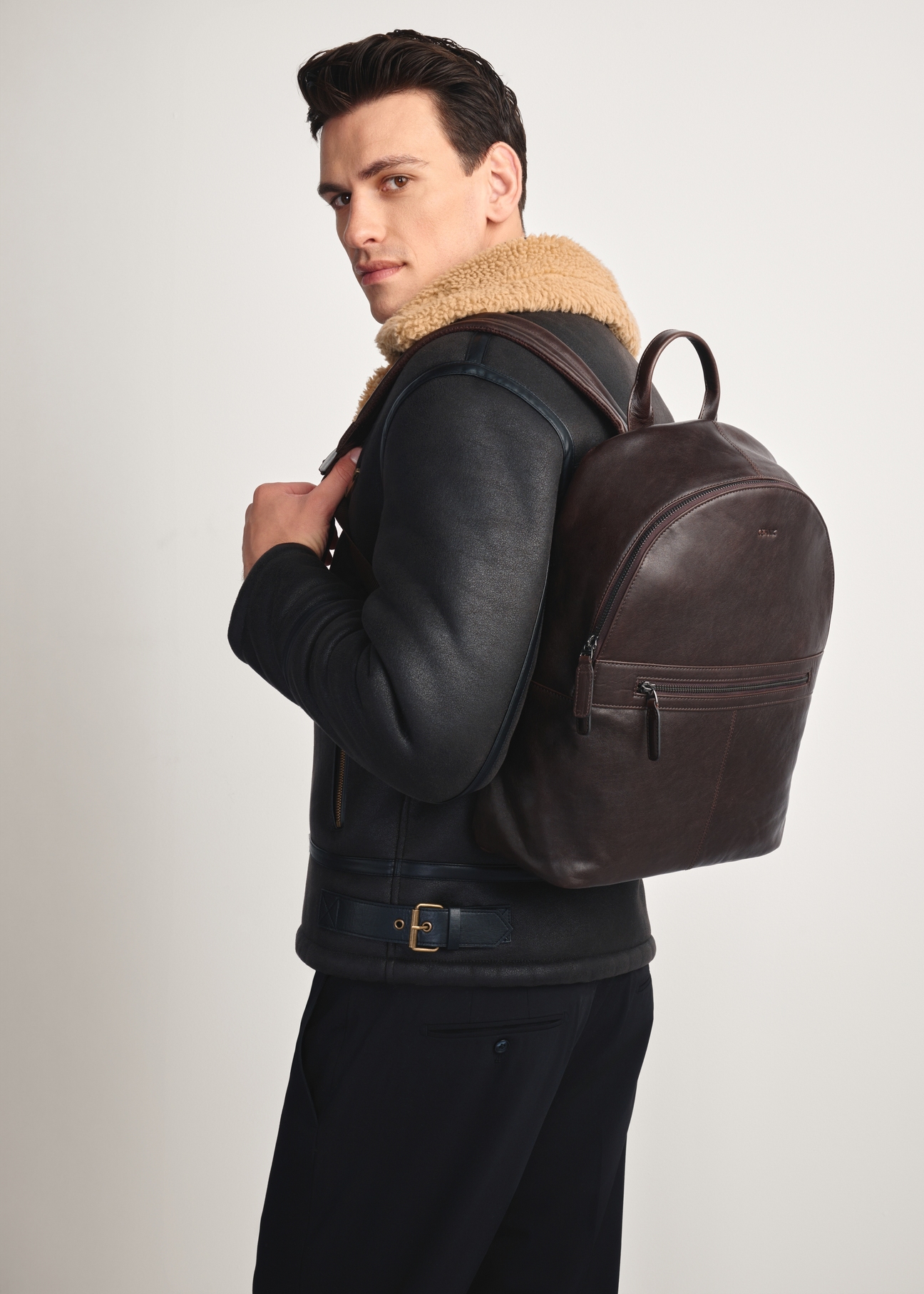 Dark brown leather men's backpack TORMS-0458-89(Z25), diagonal view of the product on the model, half of the silhouette visible.