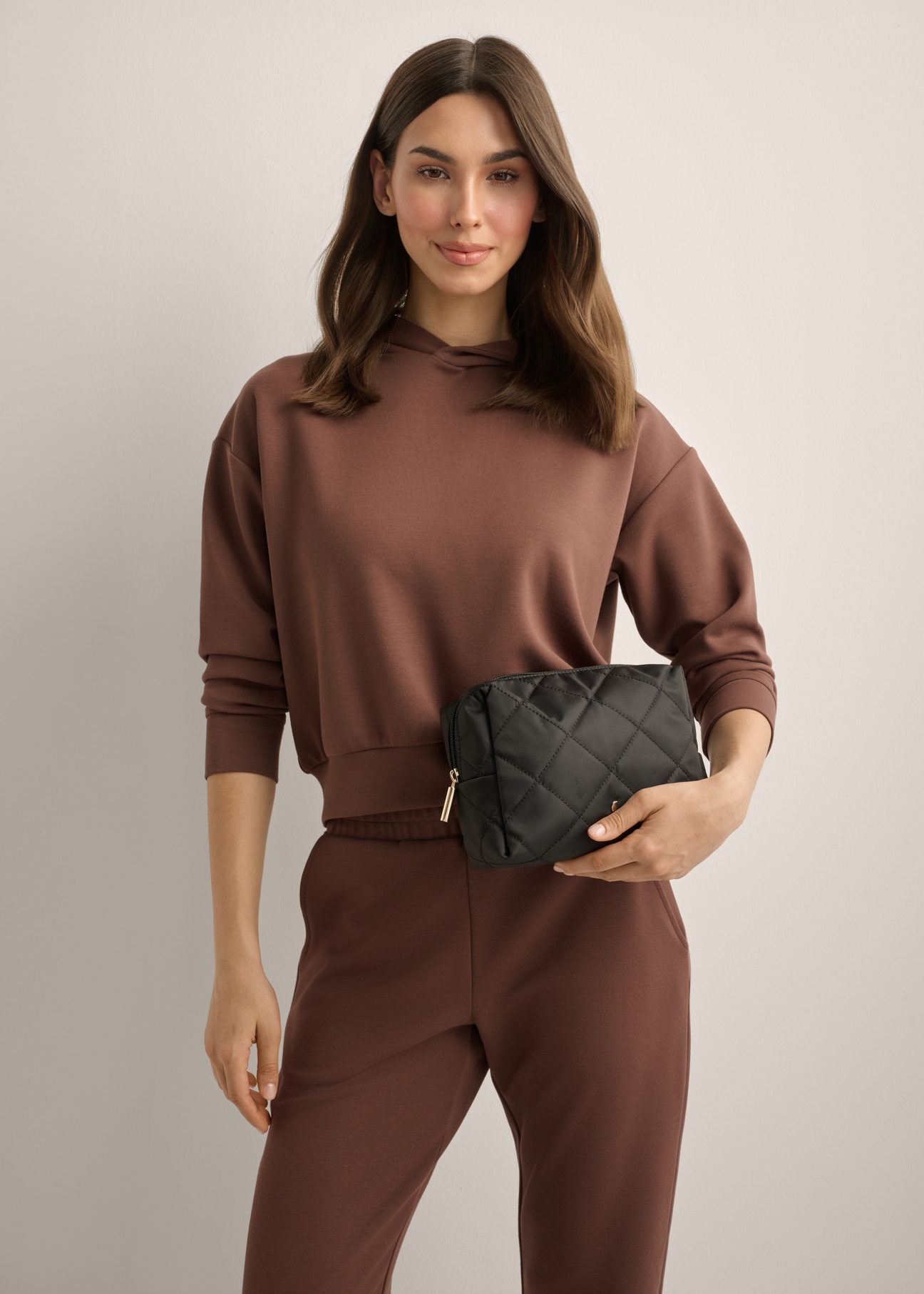 Black women's cosmetic bag TOREN-0267-9P(Z26), diagonal view of the product on the model. Half of the silhouette visible.