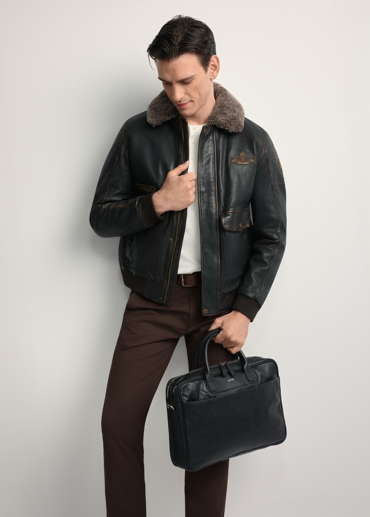 Black leather men's bag TORMS-0299A-99(Z25) - diagonal view of the product, held by the model, against a white background. Full body visible.