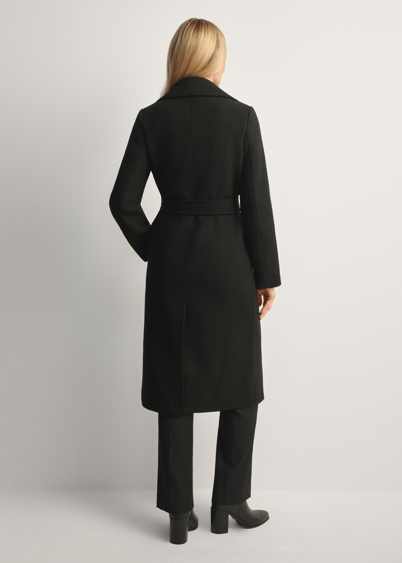 Black long women's coat PLADT-0048B-99(Z25), product view from the back on the model, the whole silhouette is visible.