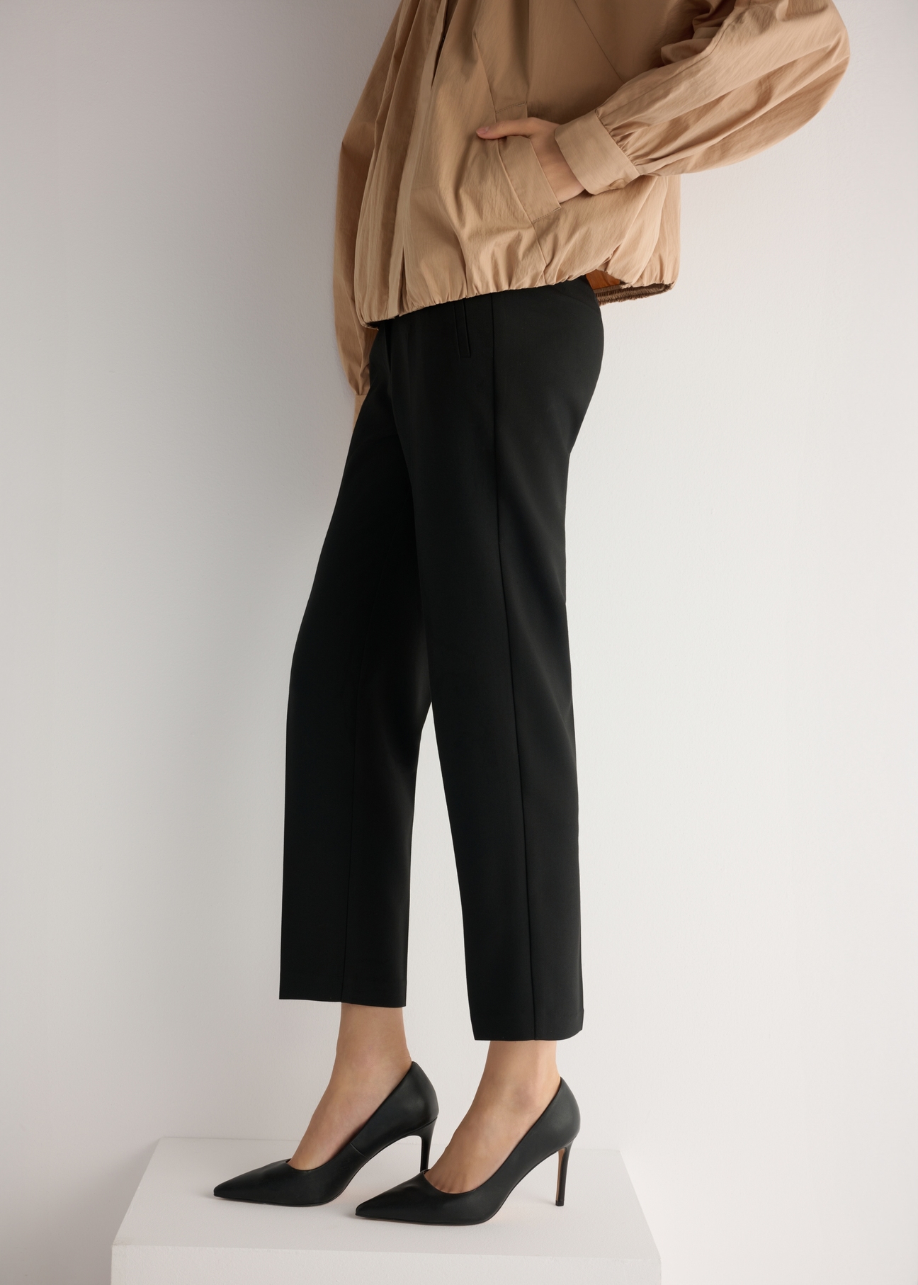 Black leather women's high heels BUTYD-1131A-99(W26), side view of the product on the model, half of the silhouette visible.