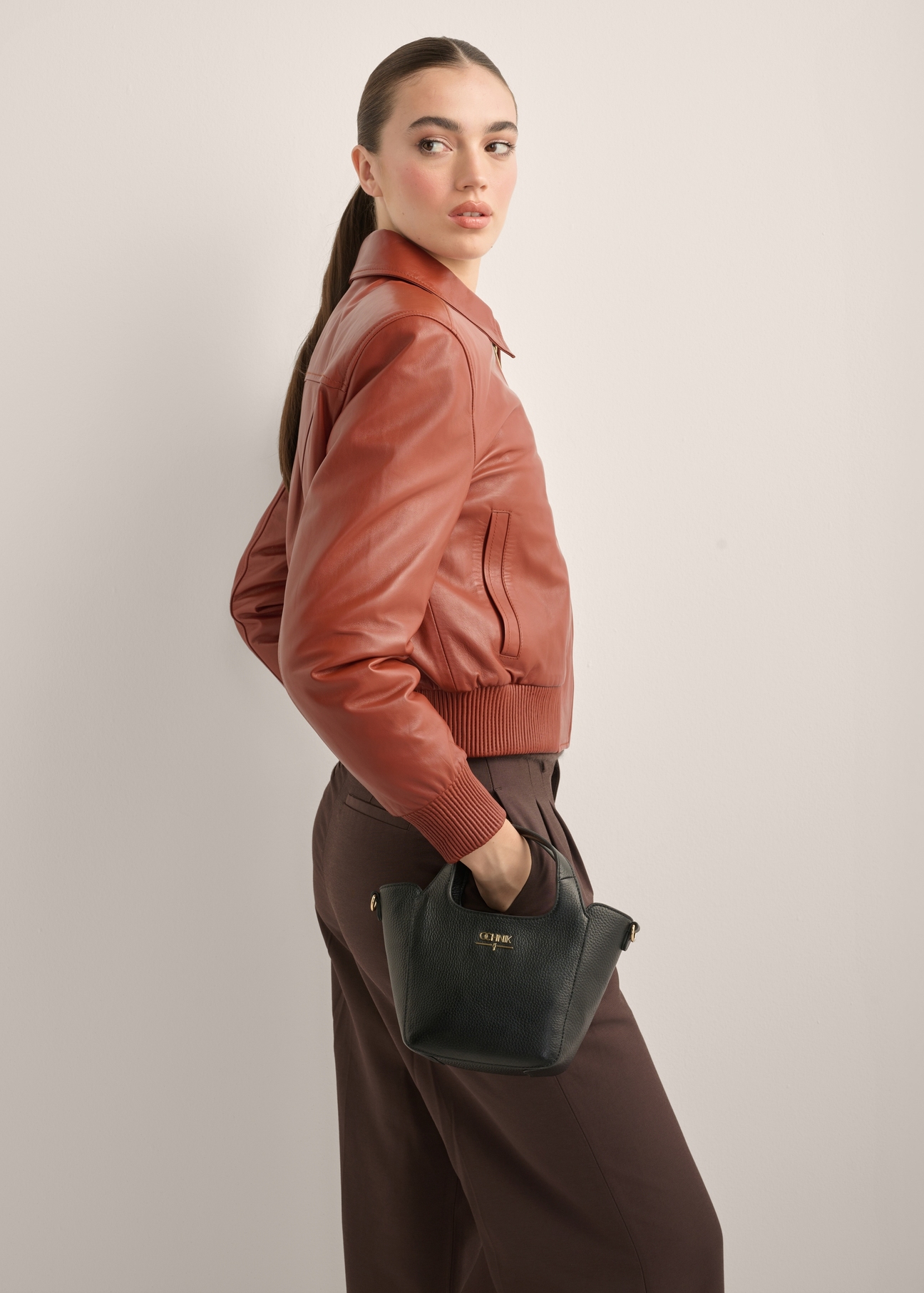 Small women's leather handbag in black TORES-1341-9I(Z26), front view of the product on a model. Half of the silhouette visible.