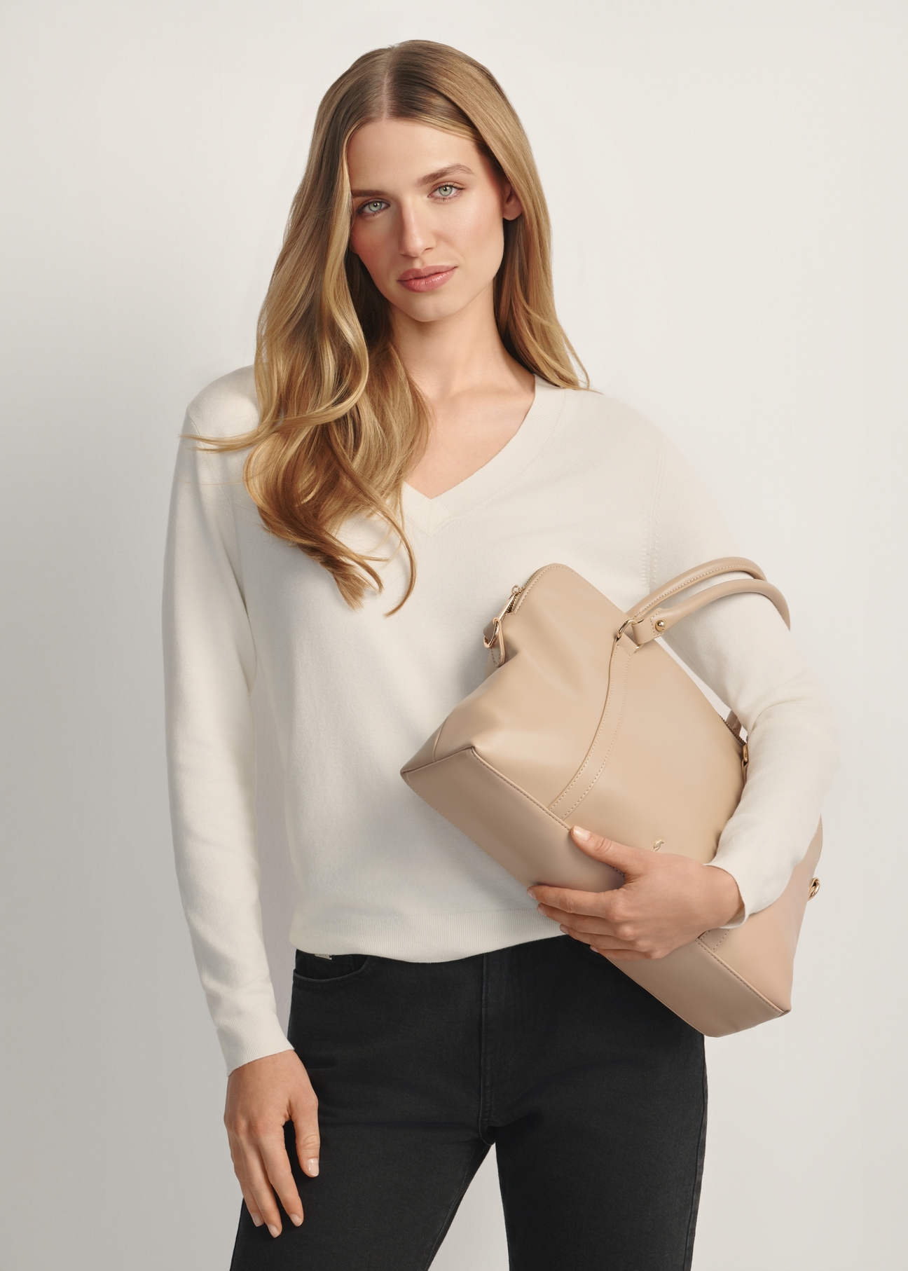 Beige women's laptop bag TOREC-1130-1A(W26) - diagonal view of the product, held by the model, against a light background. Half of the silhouette is visible.