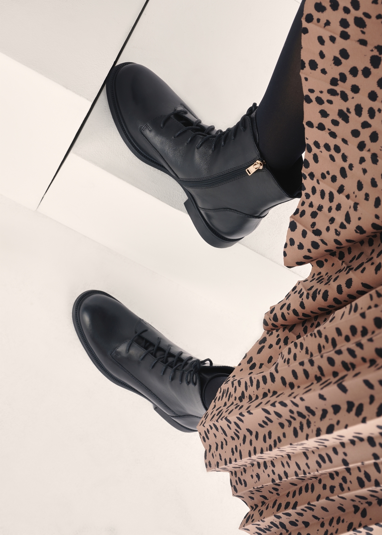 Black women's leather ankle boots BUTYD-1115-99(Z25), view of the product on the model's feet against a light background.