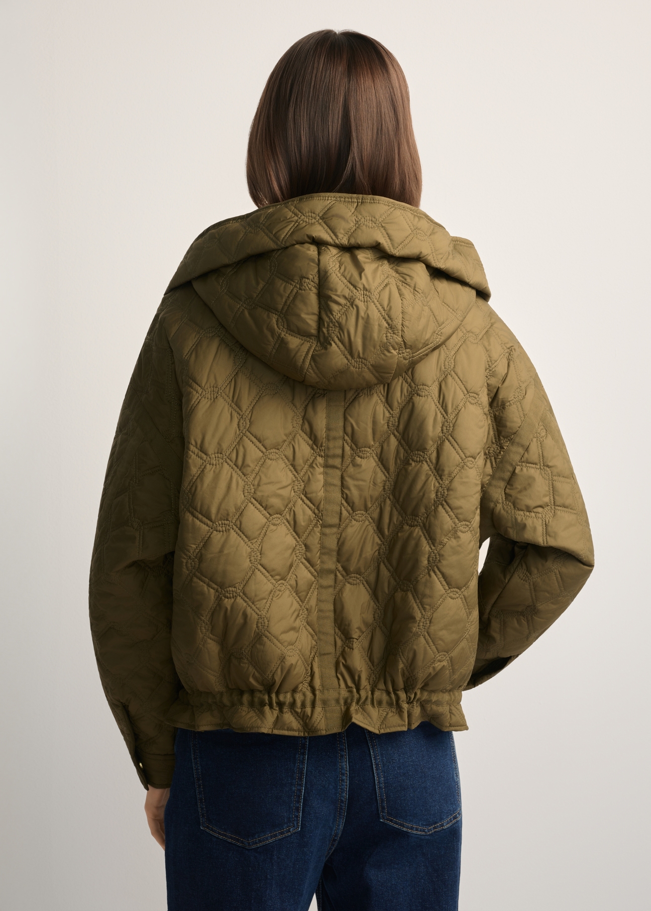 Olive green short oversized quilted jacket KURDT-0660-8D(W26) - back view of the product, on a model, against a light background. Half of the silhouette visible.