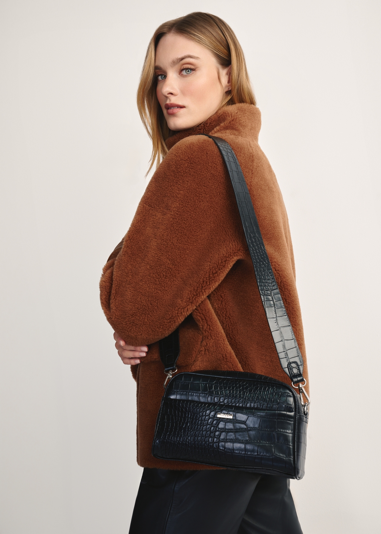 Black compact women's handbag TOREC-1069-99(Z25), front view of the product on a model, half of the silhouette visible.