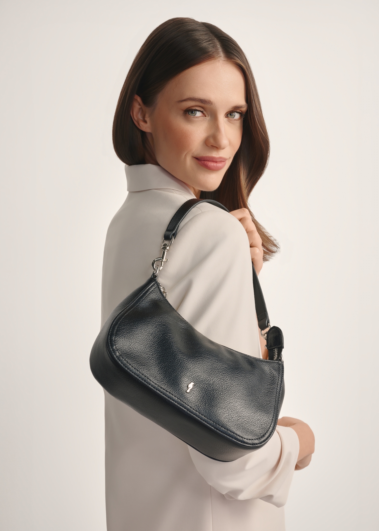 Small black women's handbag TOREC-1134-99(W26) - front view of the product, on a model, against a white background. Half of the silhouette visible.