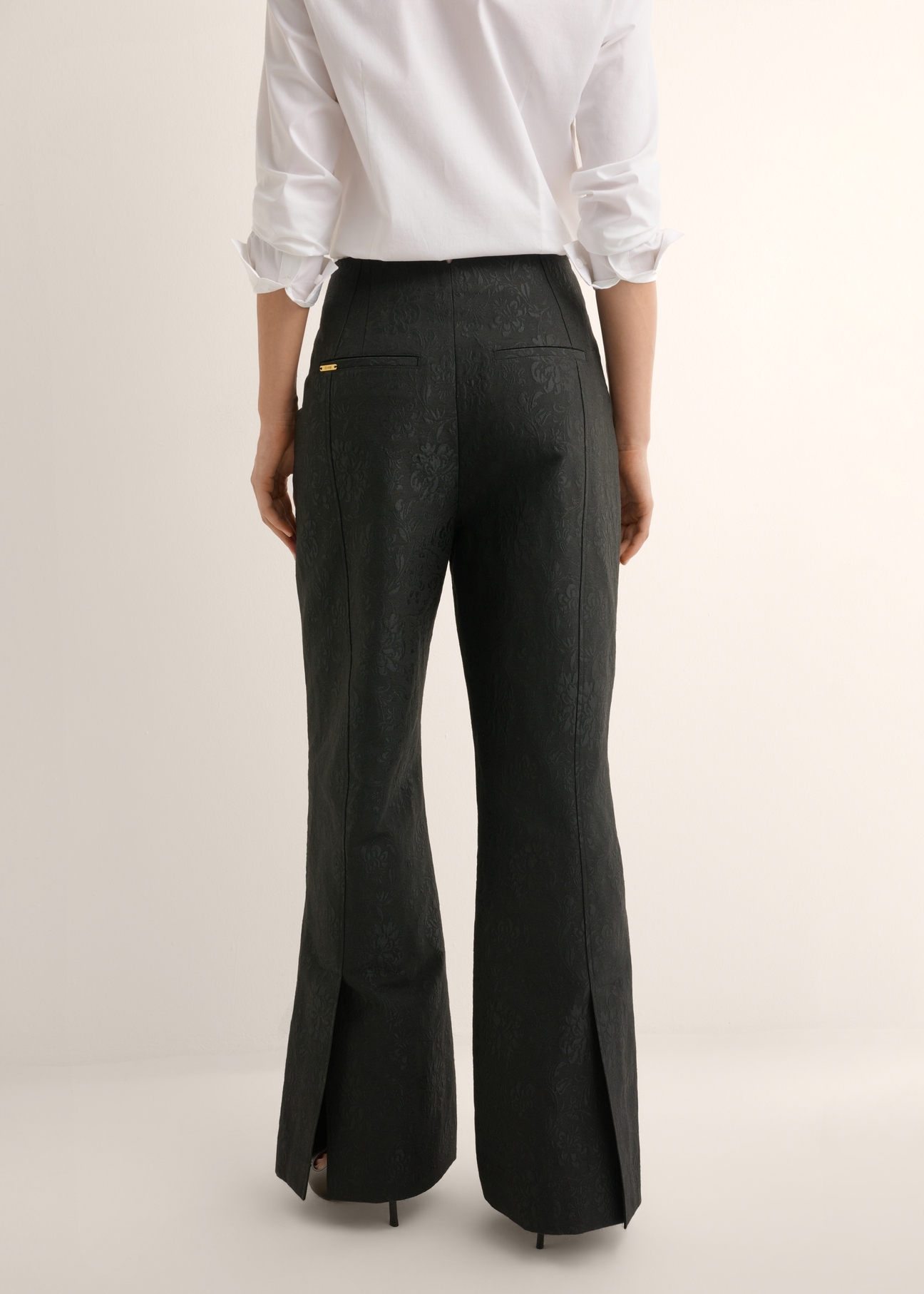 Black floral wide leg trousers SPODT-0127-99(Z26), back view of the product on the model. Half of the silhouette visible.