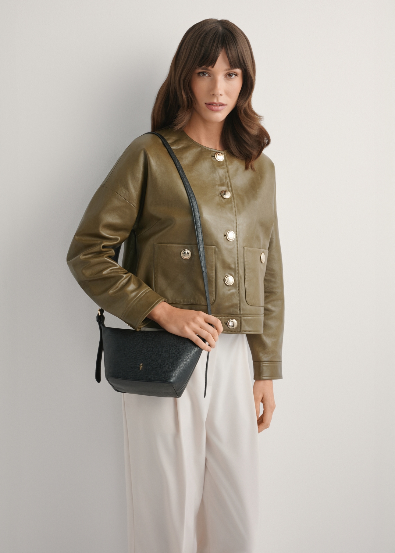 Small black handbag made of natural leather TORES-1267-9I(W26), front view of the product on a model, half of the silhouette visible.