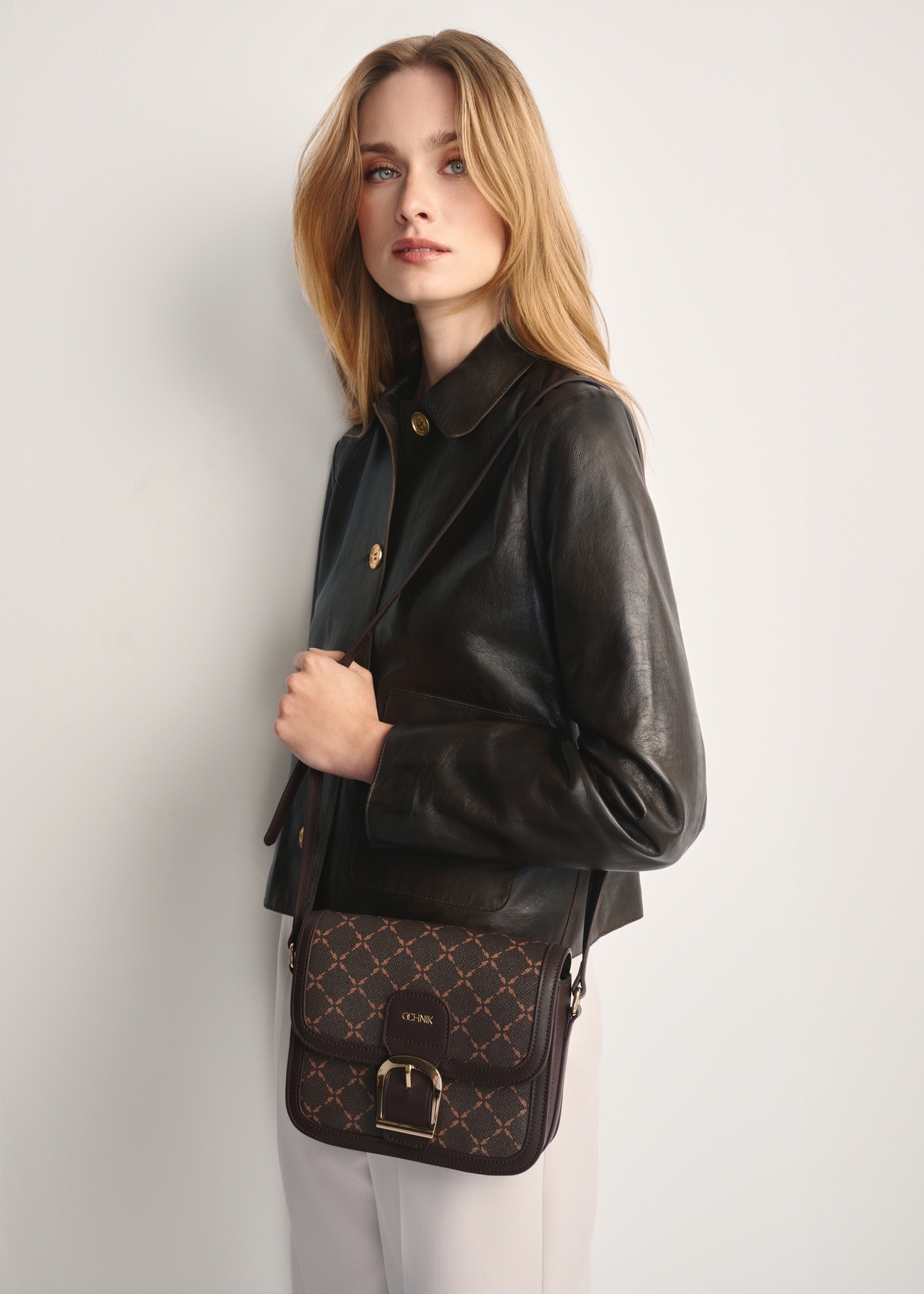 Brown messenger bag with monogram TOREC-0982A-89(Z25), front view of the product on a model, half of the silhouette visible.