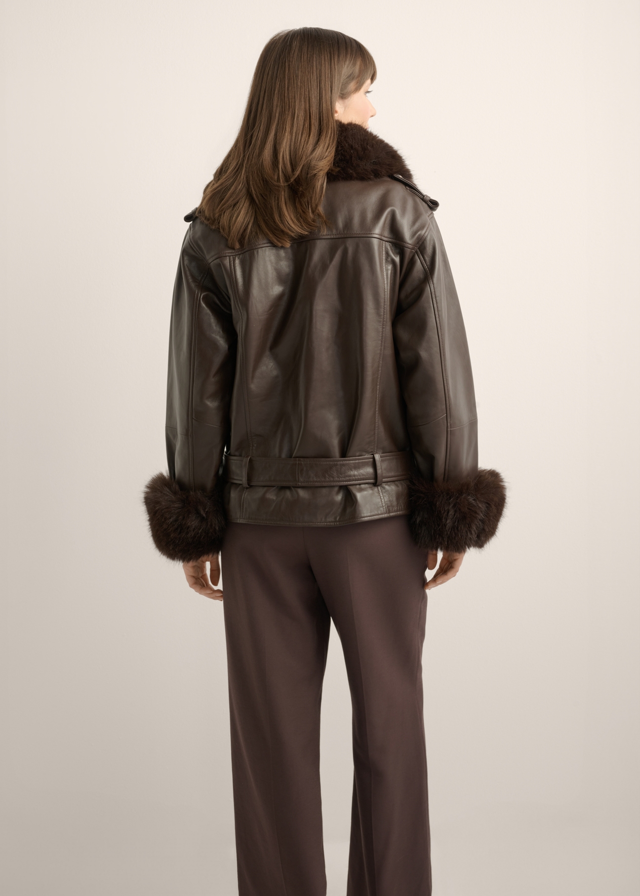 Women's dark brown leather jacket KURDS-0616-1I(Z26) - back view of the product, on a model, against a light background. Half of the silhouette visible.