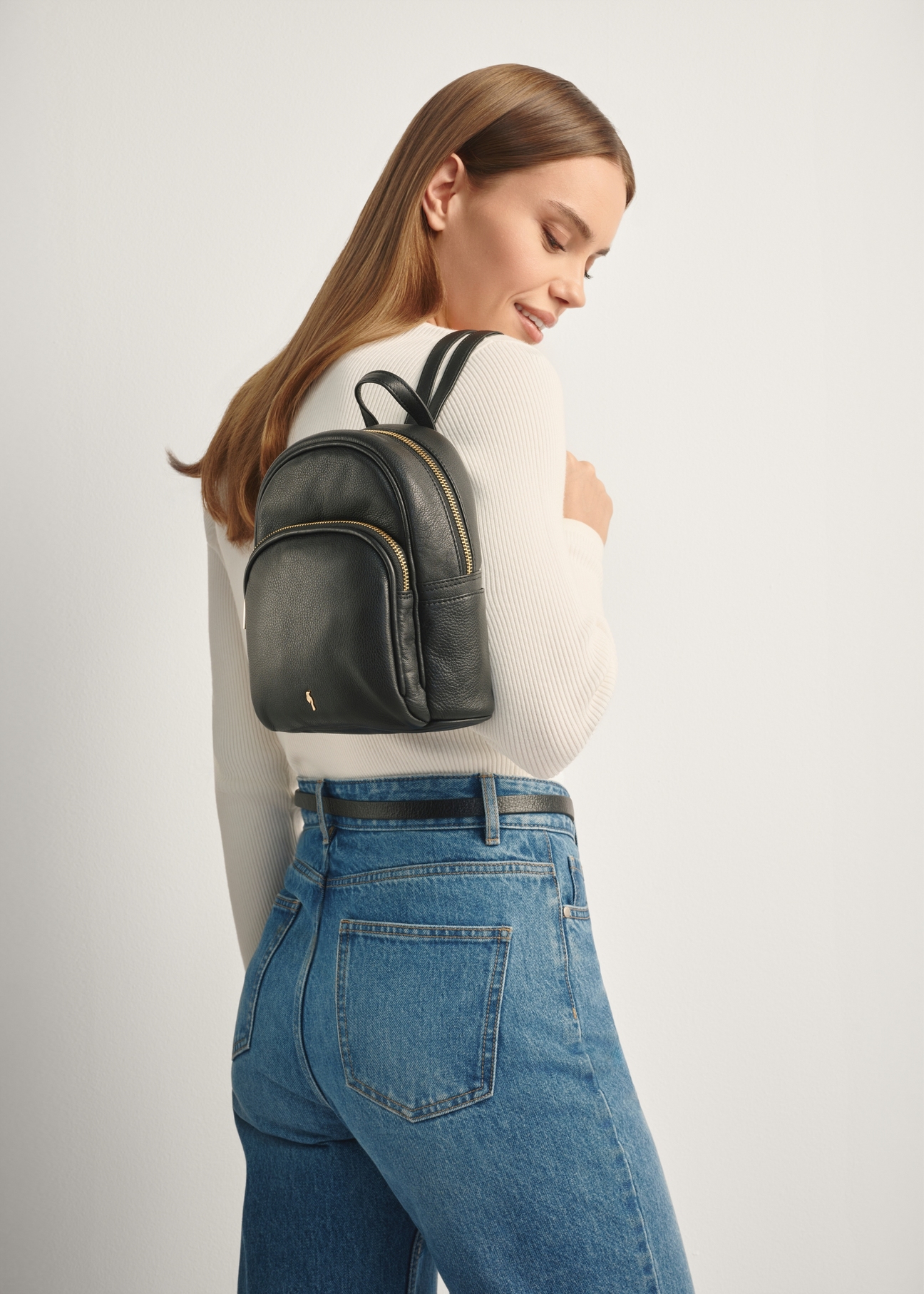 Black leather women's backpack TORES-1089A-99(W26), front view of the product on a model, half of the silhouette visible.