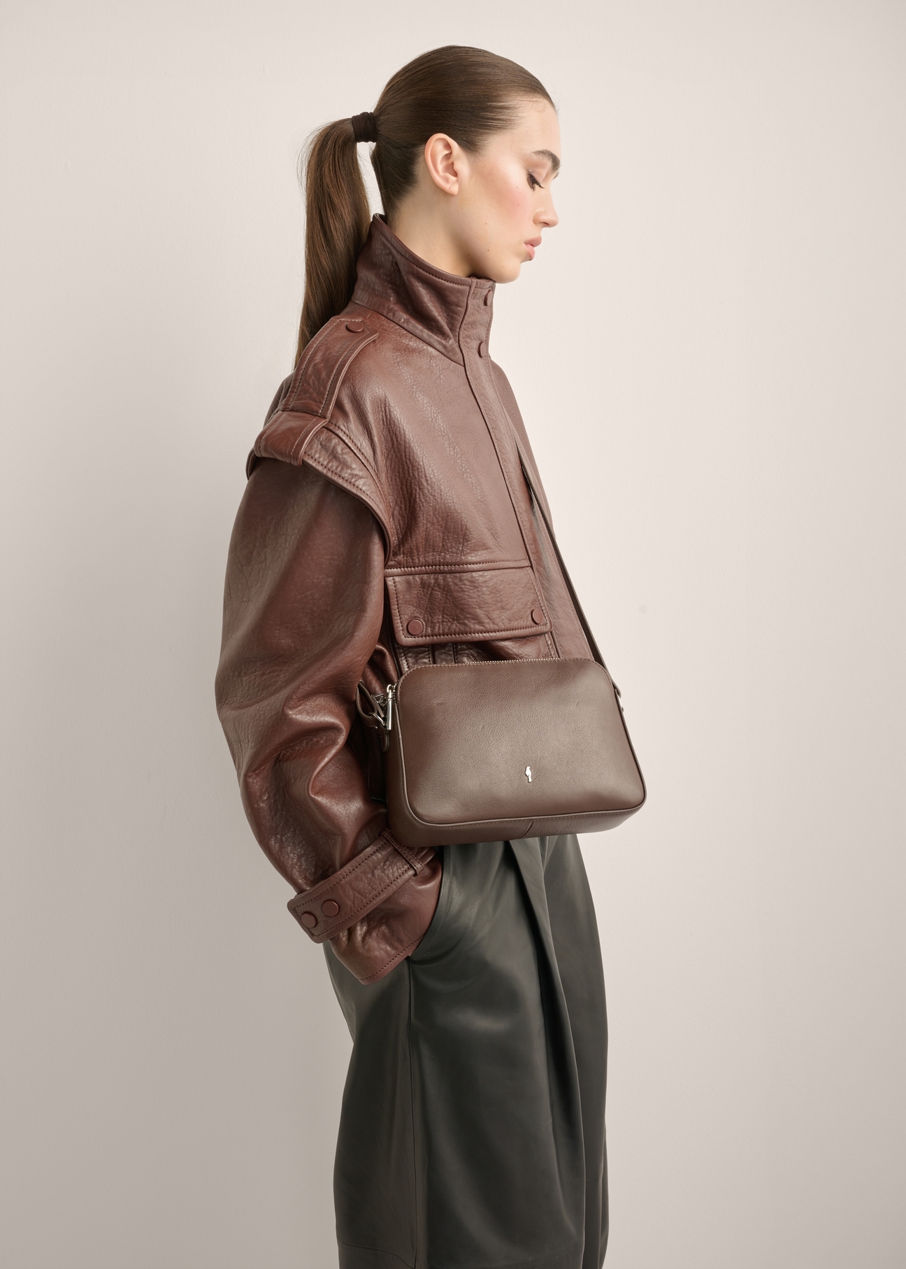 Small brown leather women's handbag TORES-1353-1H(Z26), diagonal view of the product on the model. Half of the silhouette visible.