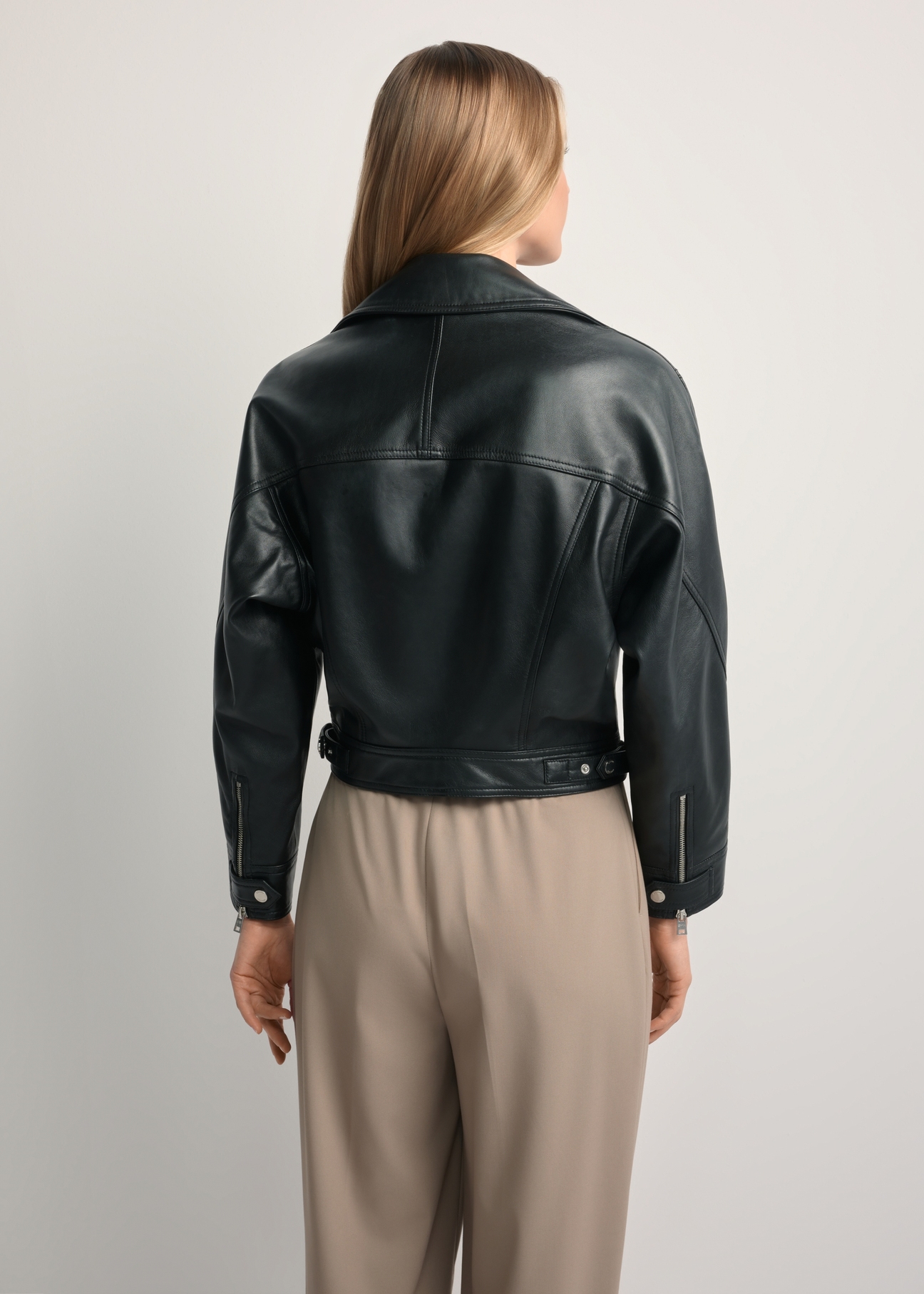 Women's short black leather jacket KURDS-0607-99(W26) - back view of the product, on a model, against a light background. Half of the silhouette visible.