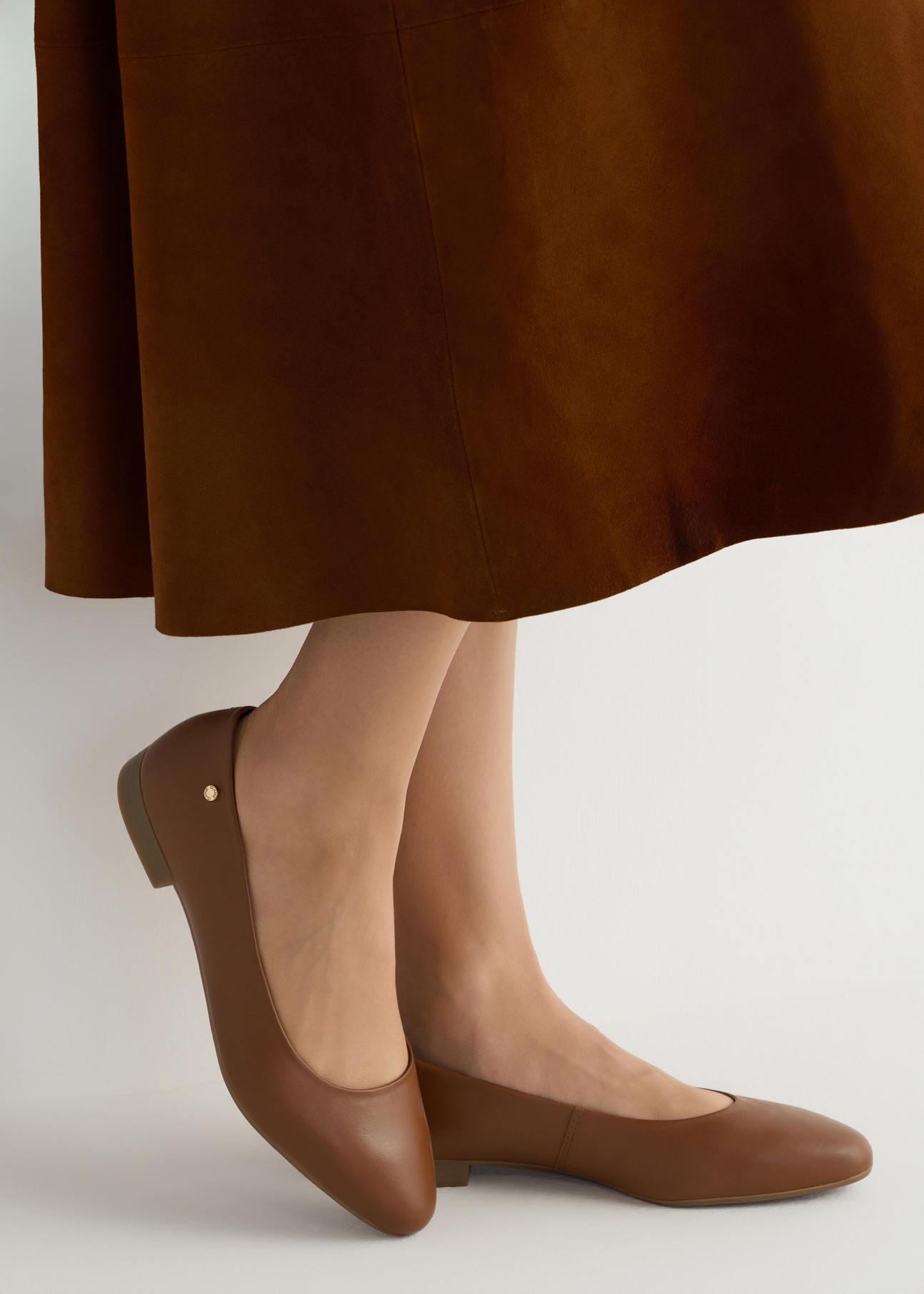 Women's leather ballet flats in cognac color BUTYD-1049B-1F(W26), side view of the product on the model, half of the silhouette visible.