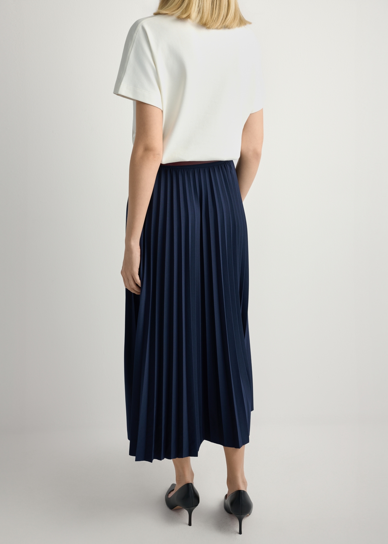 Navy blue pleated midi skirt SPCDT-0096-7E(W26), back view of the product on the model. Half of the silhouette visible.