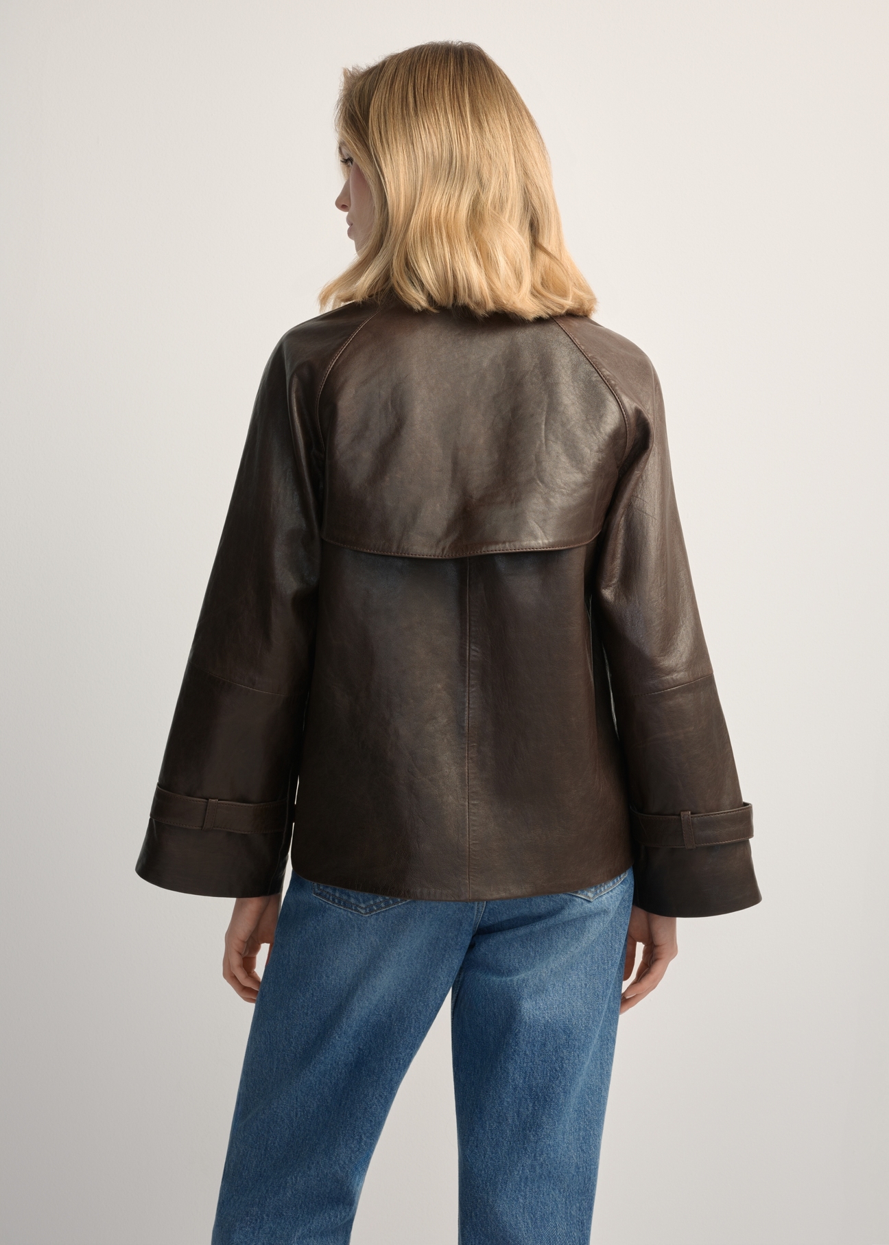 Women's dark brown leather jacket KURDS-0604-1I(W26), back view of the product on the model. Half of the silhouette visible.